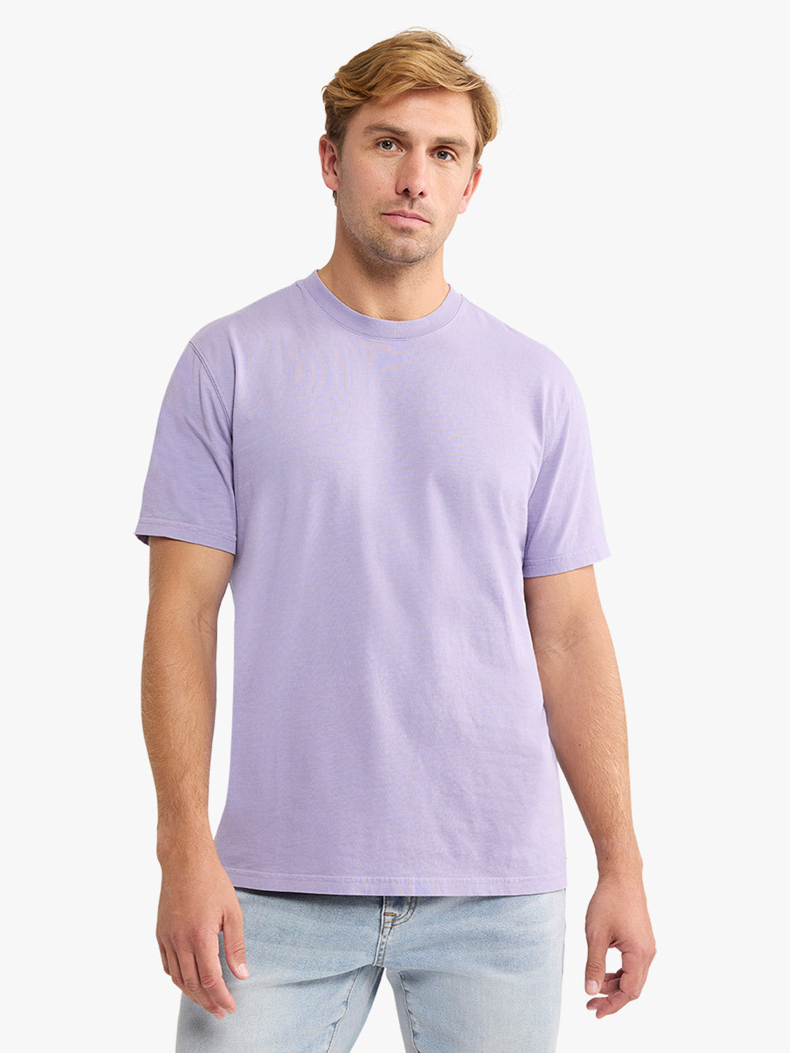 Man wearing a lavender short-sleeve crew neck t-shirt with light blue jeans.