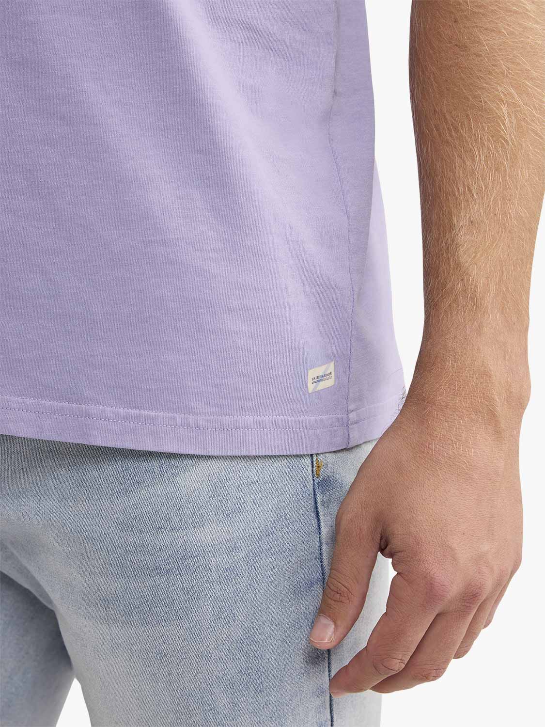 Man wearing a light purple short-sleeved t-shirt with a small label on the side seam.