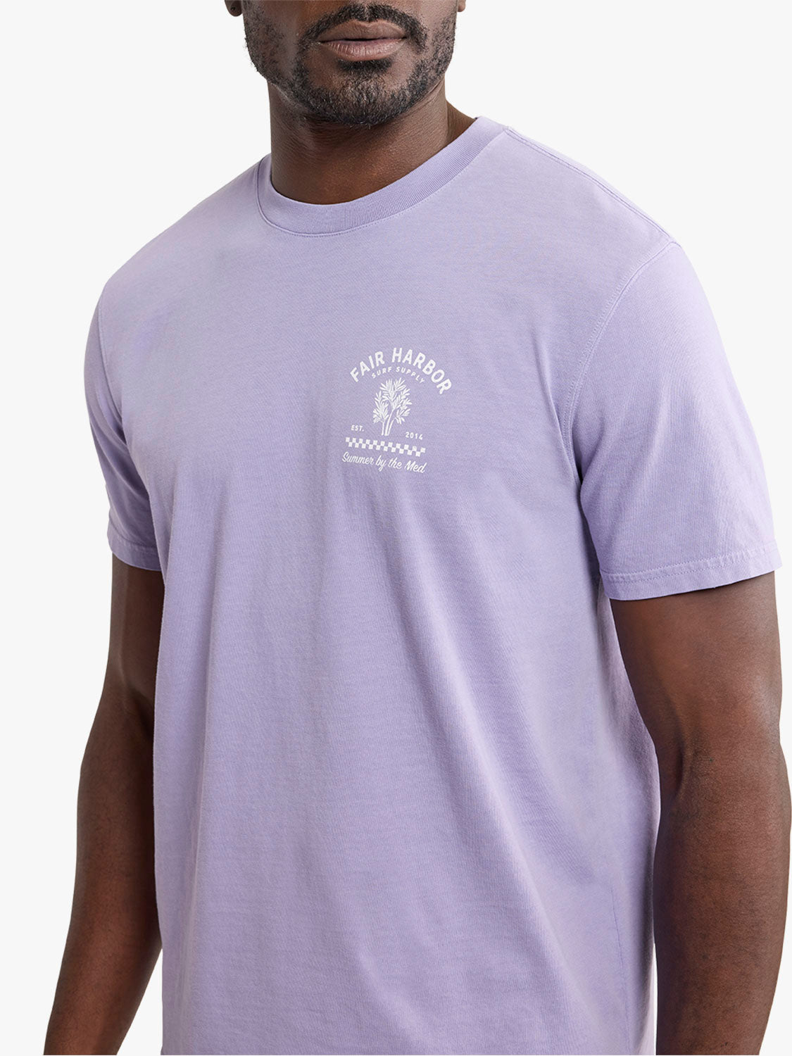 Man wearing a light purple short-sleeve t-shirt with a small graphic design and text on the chest.