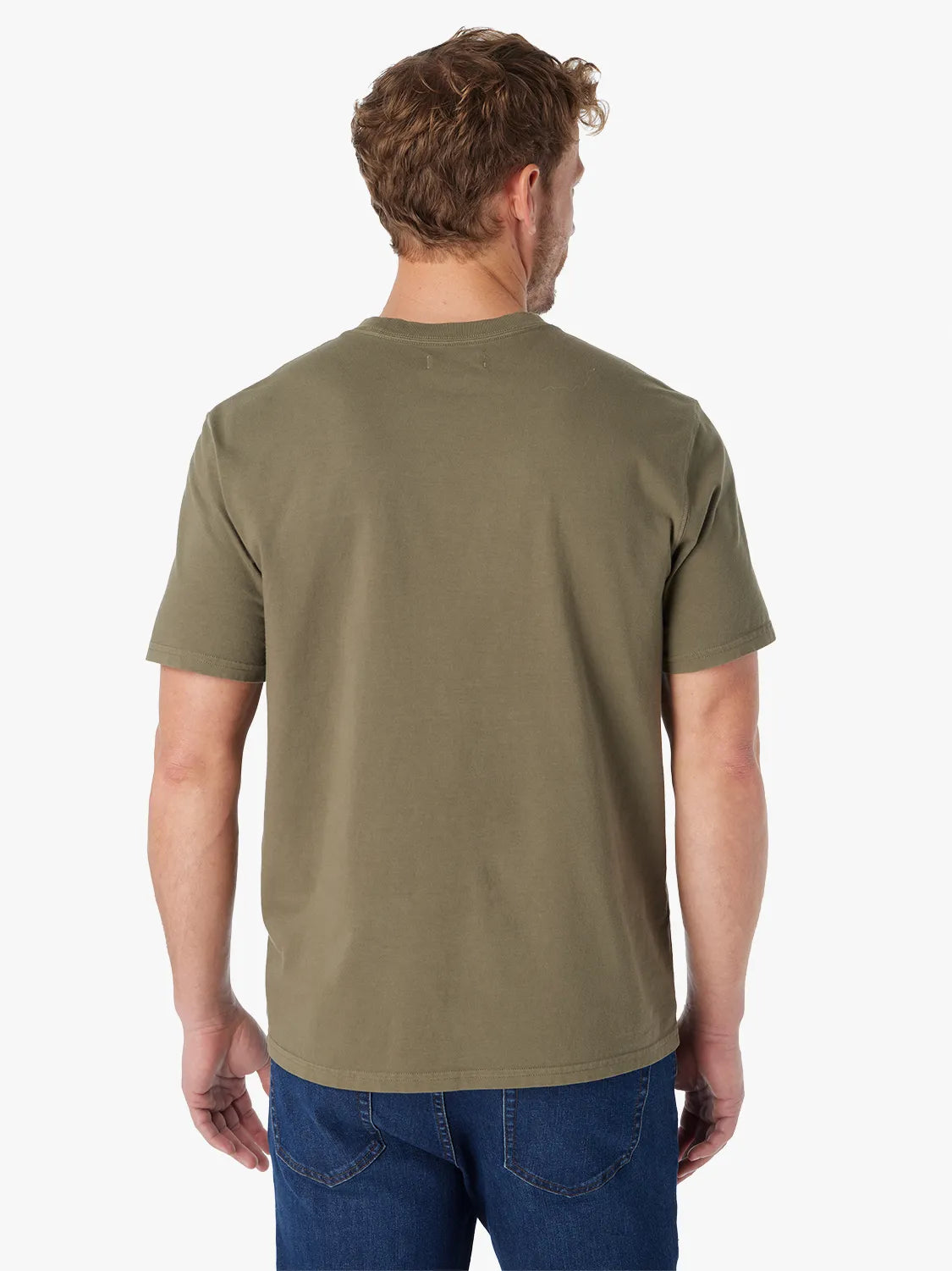 Man wearing olive green saltaire t-shirt on a white background paired with a pair of driftwood denim. Showing the back view of t-shirt. 