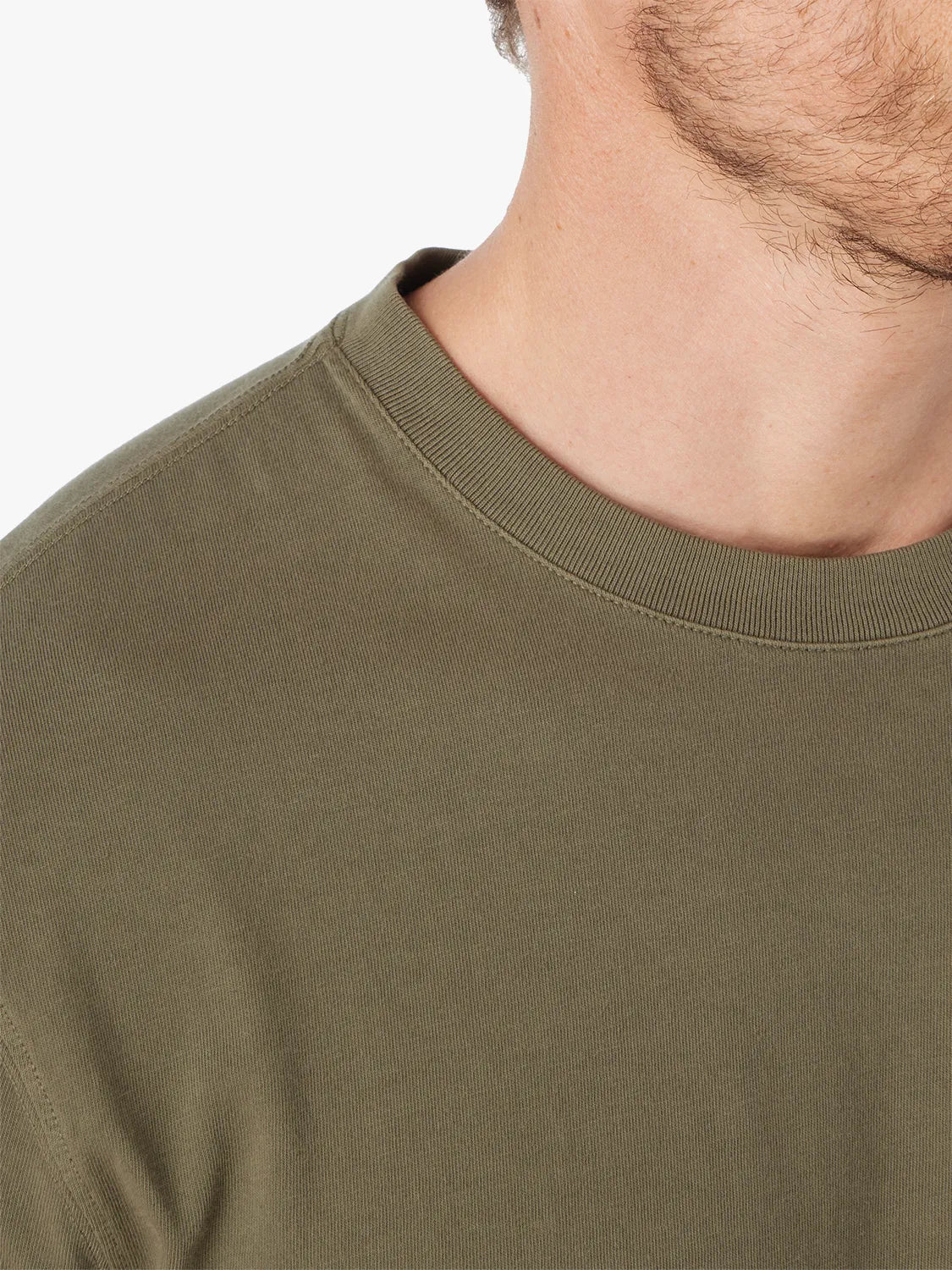 Close-up of a person wearing an olive green saltaire t-shirt against a white background