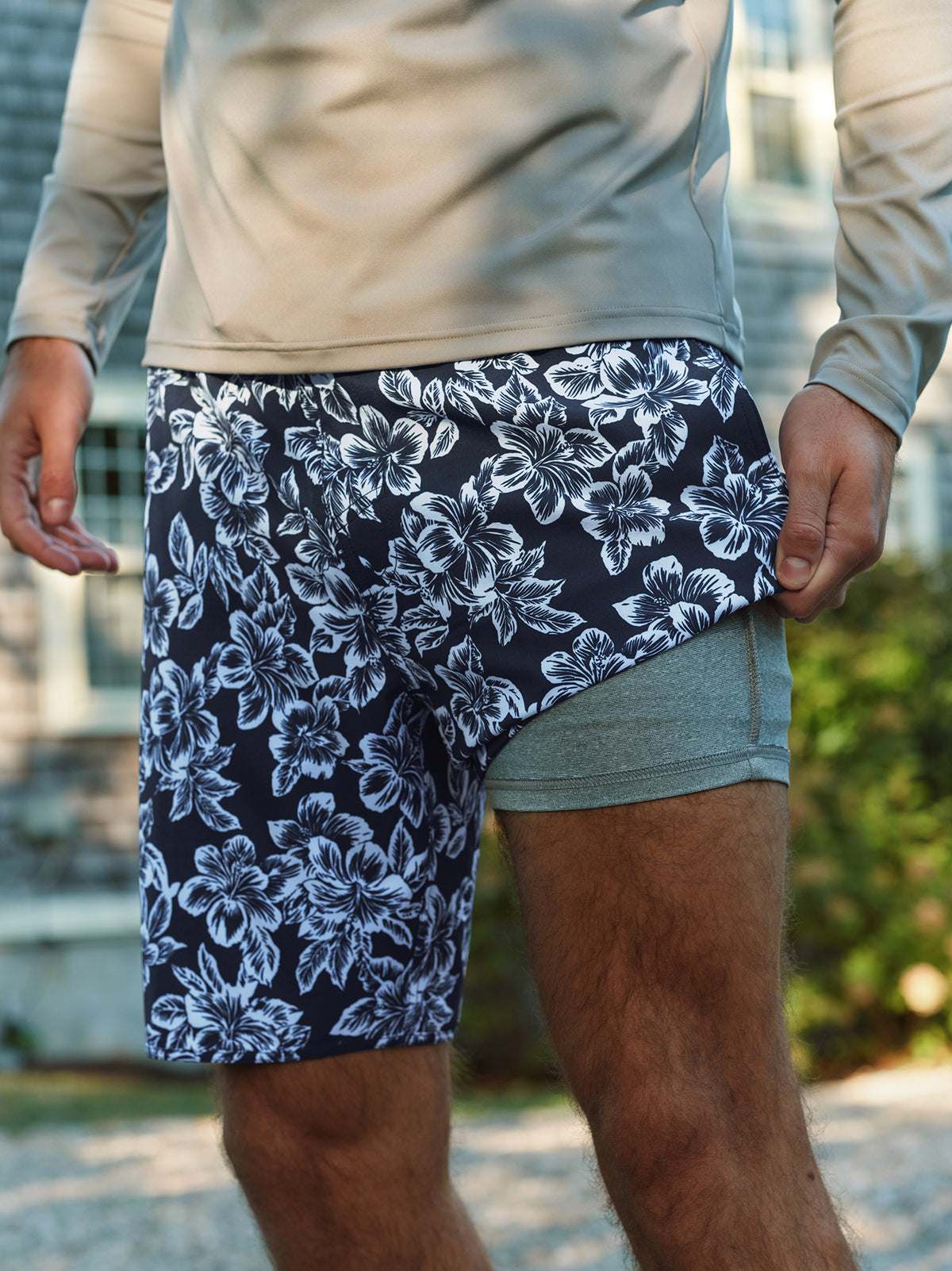 Man wearing navy swim trunks with white floral anchor pattern and blue-green swim shorts.