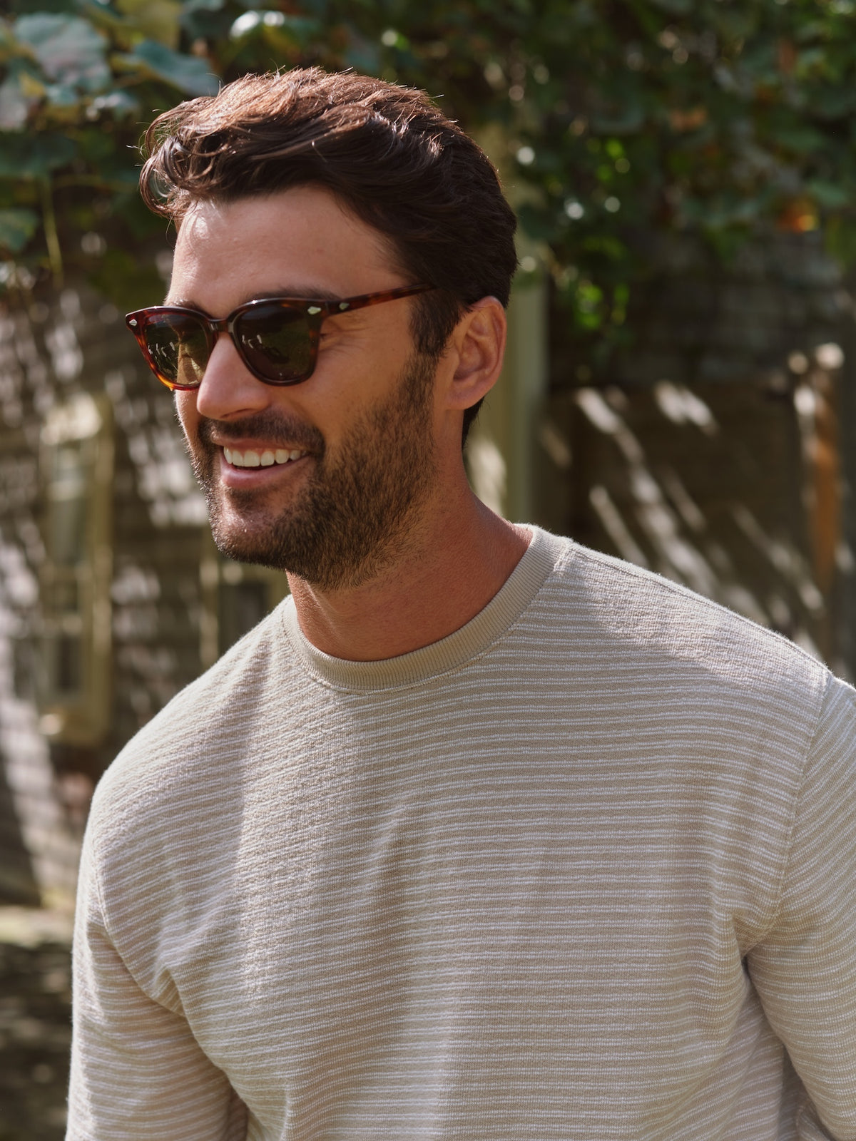 Man wearing a cream and white striped crewneck terry sweatshirt in an outdoor setting.
