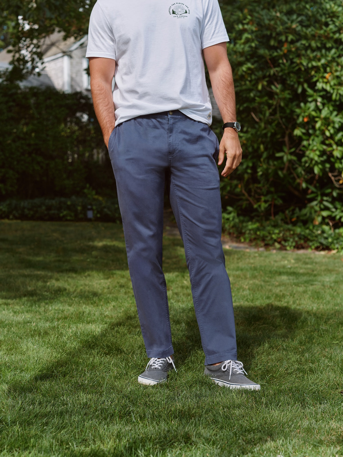 Man wearing a light blue pull-on pant with elastic waistband standing outdoors on grass.