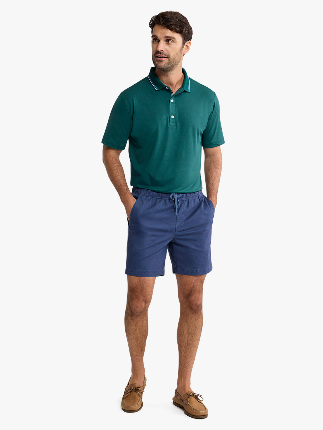 Man wearing a fairway green short-sleeve polo shirt with white-tipped collar and navy shorts.