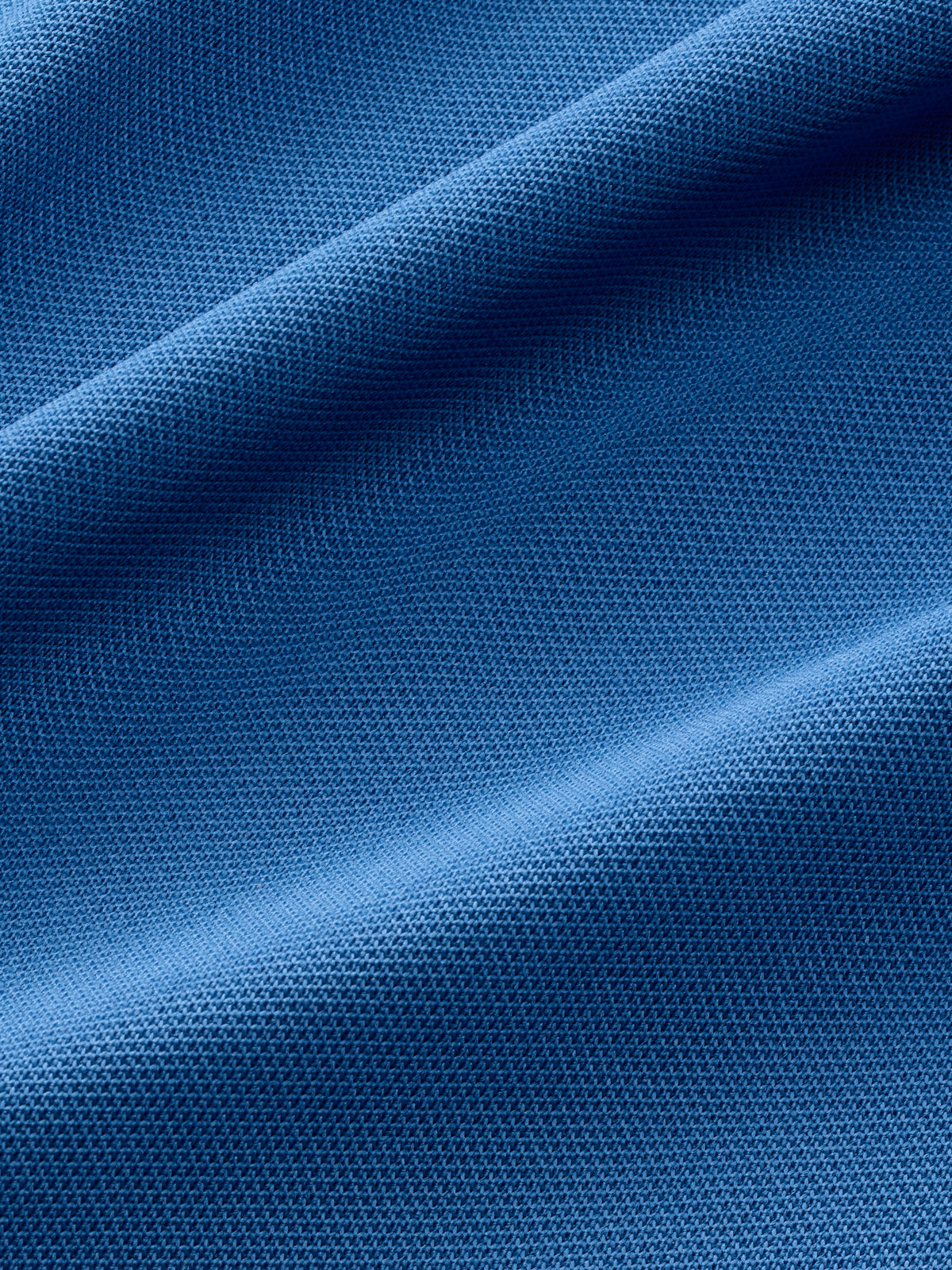 Ocean blue piqué polo fabric with textured weave and diagonal fold detail.