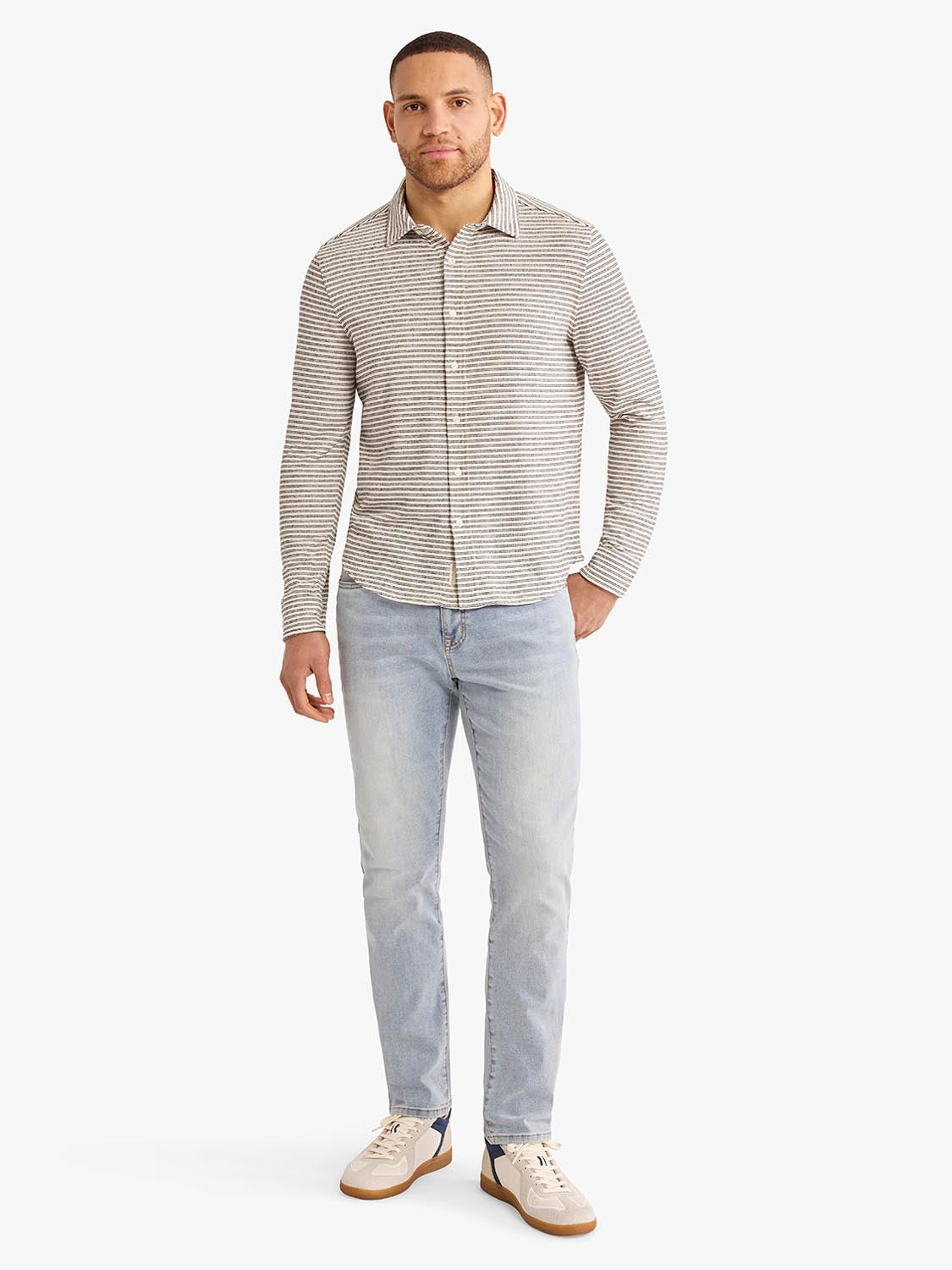 Man wearing a long-sleeve button-up shirt with horizontal stripes in beige and white tones.