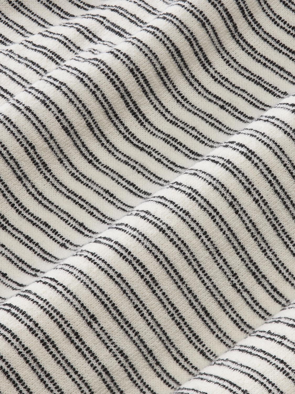 Terry fabric with black diagonal stripes running across a cream-colored textured background.