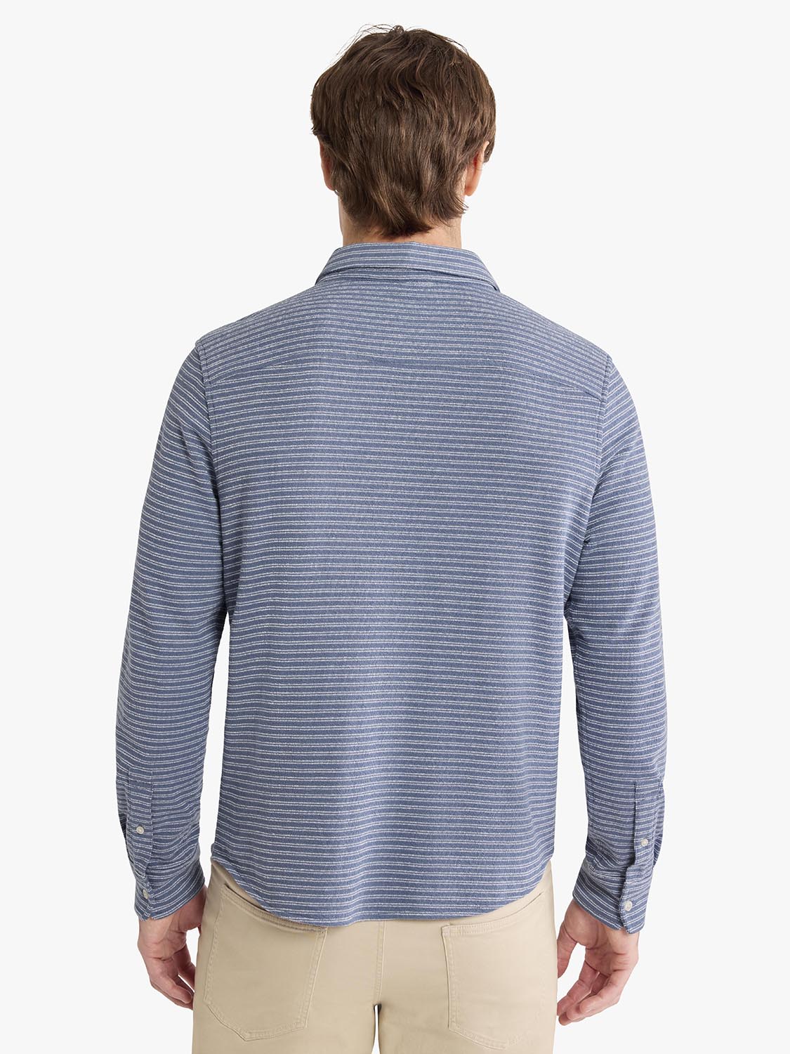 Man wearing a blue and white striped button-up shirt with long sleeves from behind.