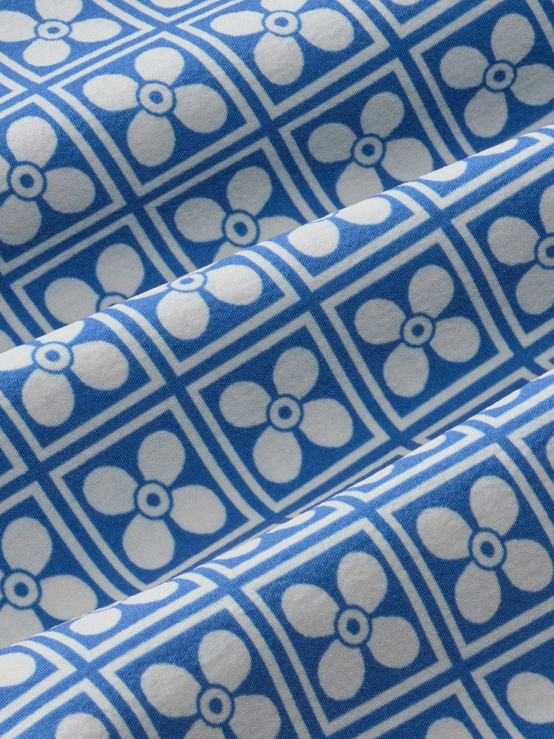 Blue board short fabric featuring a geometric floral pattern with white and gray circles.