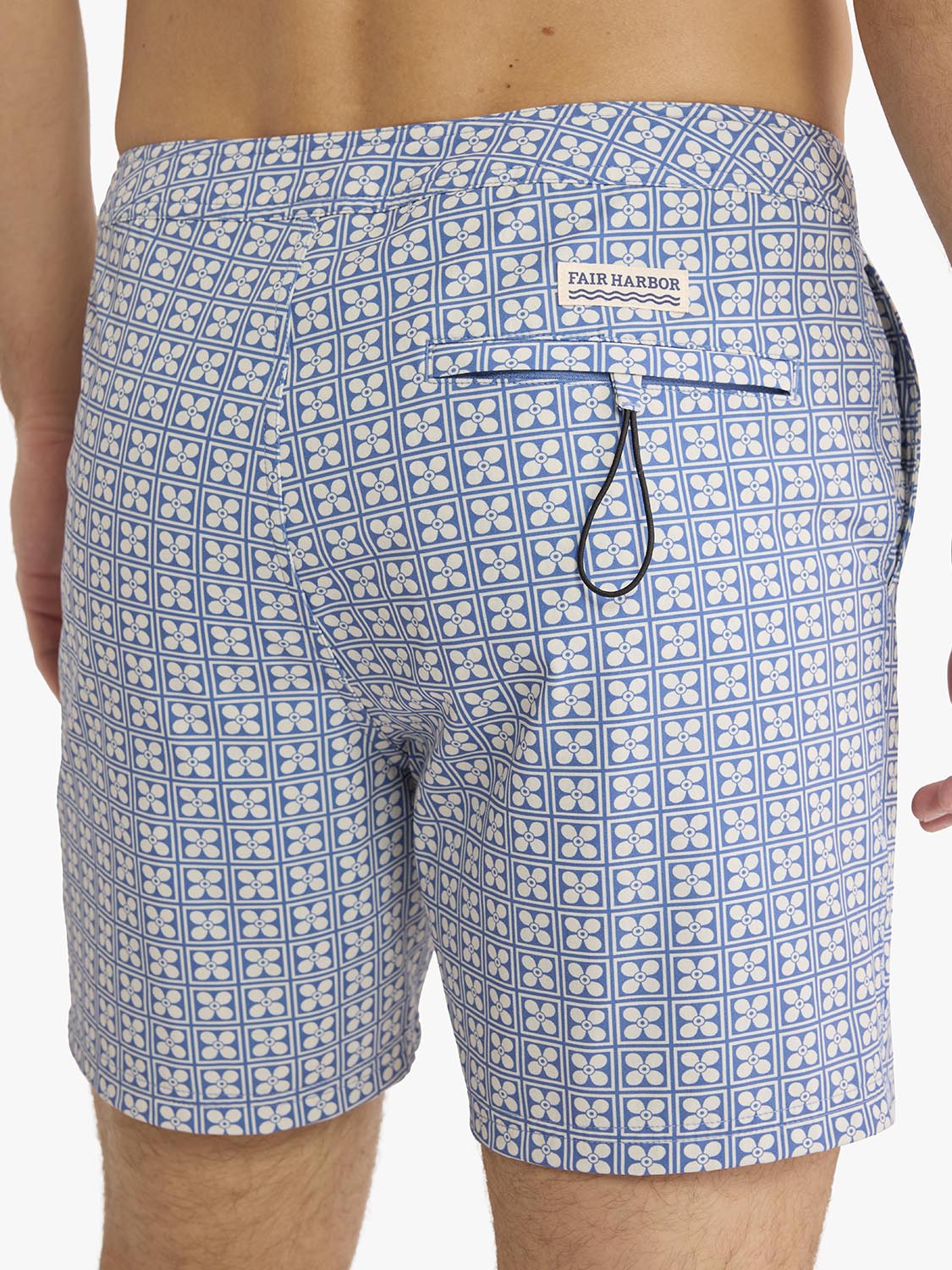 Men's blue and white board shorts with geometric floral pattern and drawstring waist.