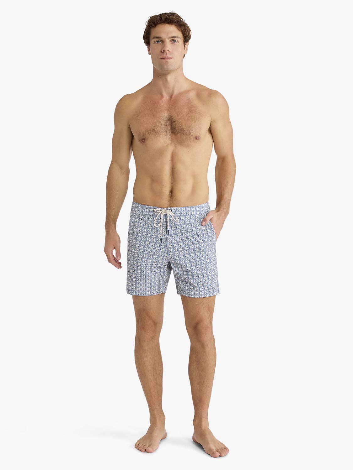 Man wearing blue board shorts with a small geometric flower pattern and drawstring waist.