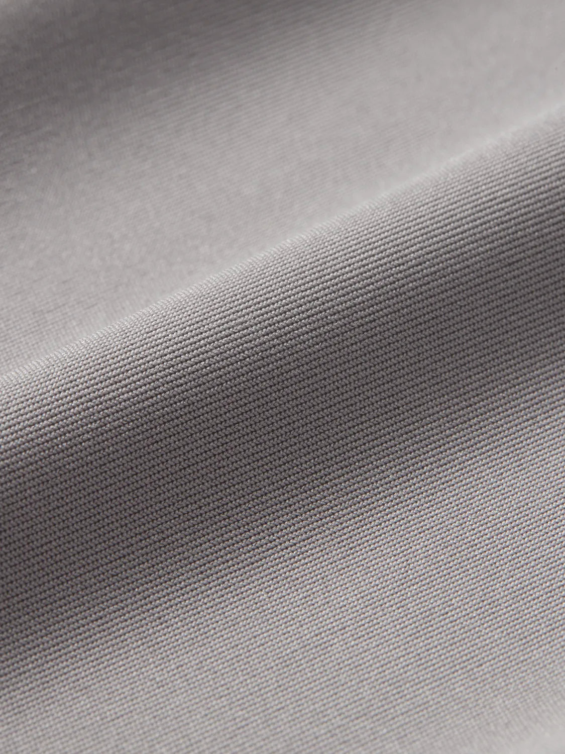 Close-up view of grey rashguard fabric showing textured knit weave and surface detail.