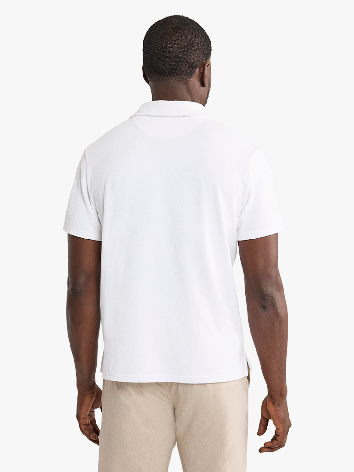 Man wearing a white short-sleeve polo shirt with a collared neckline and khaki pants, photographed from behind.