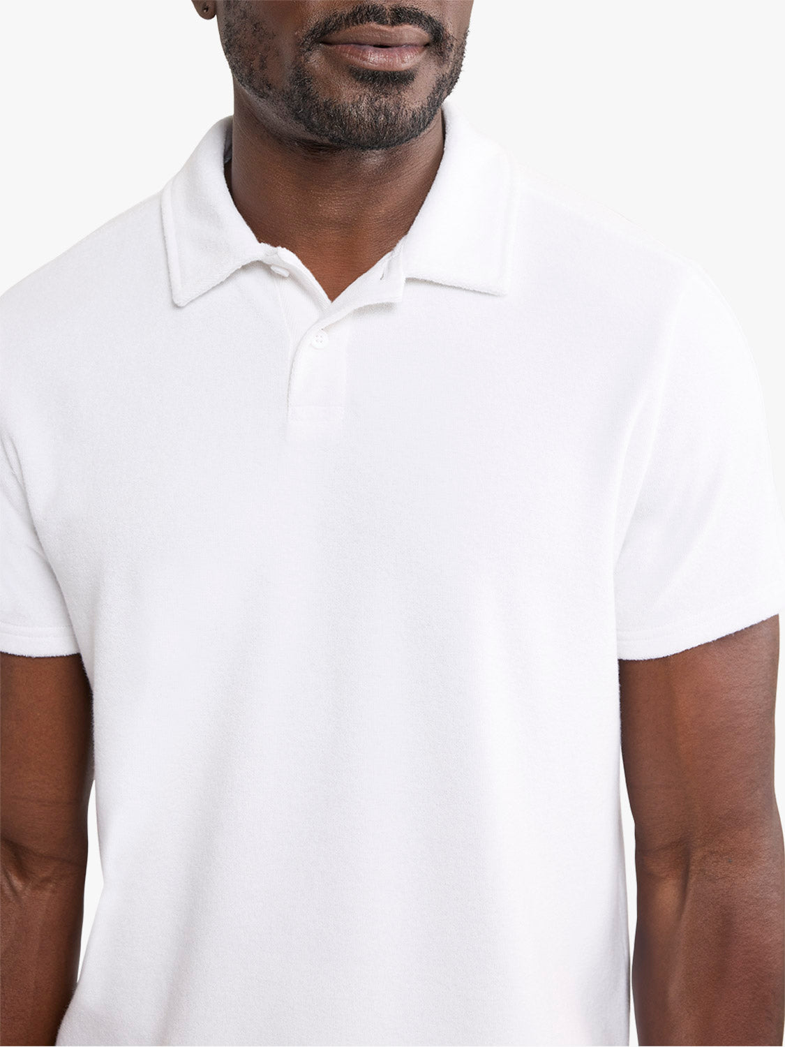 Man wearing a white short-sleeve polo shirt with a ribbed collar and button placket.