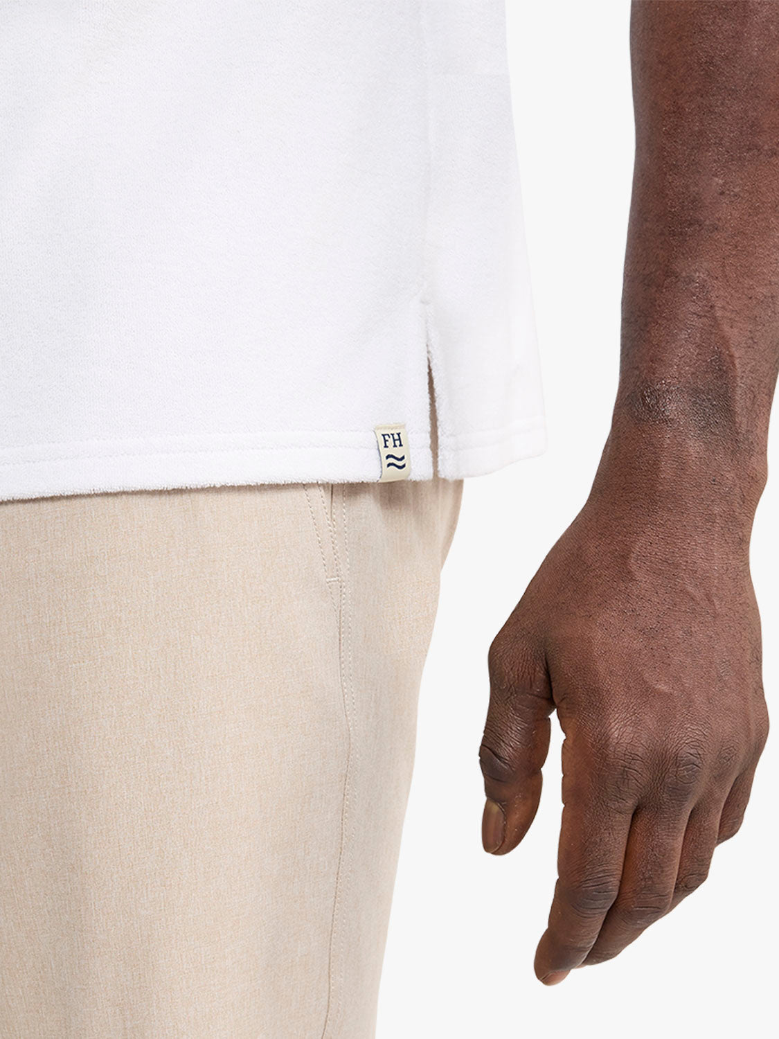 White terry polo shirt with beige pants and brand label visible on wearer.