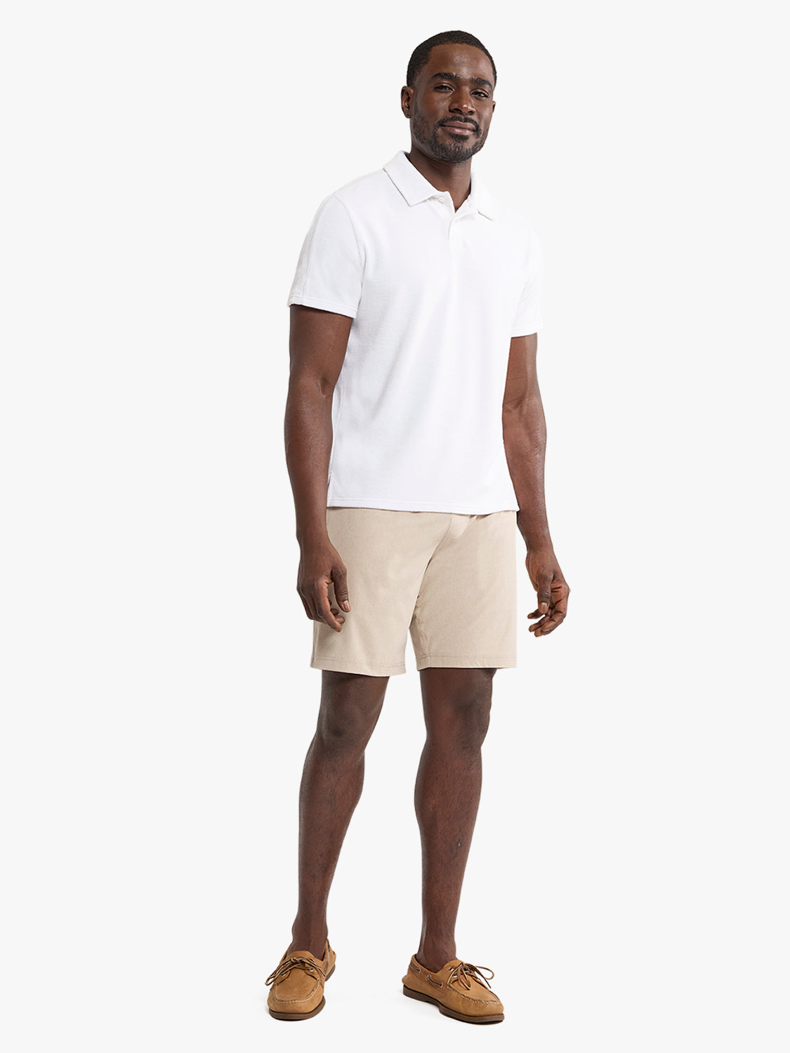 Man wearing a white short-sleeve polo shirt with beige shorts and brown boat shoes.