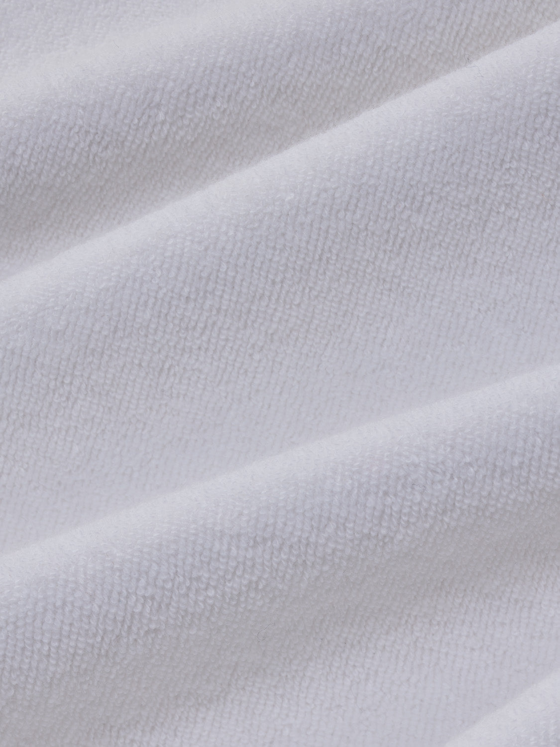 White terry cloth fabric with a textured surface and subtle diagonal folds throughout.