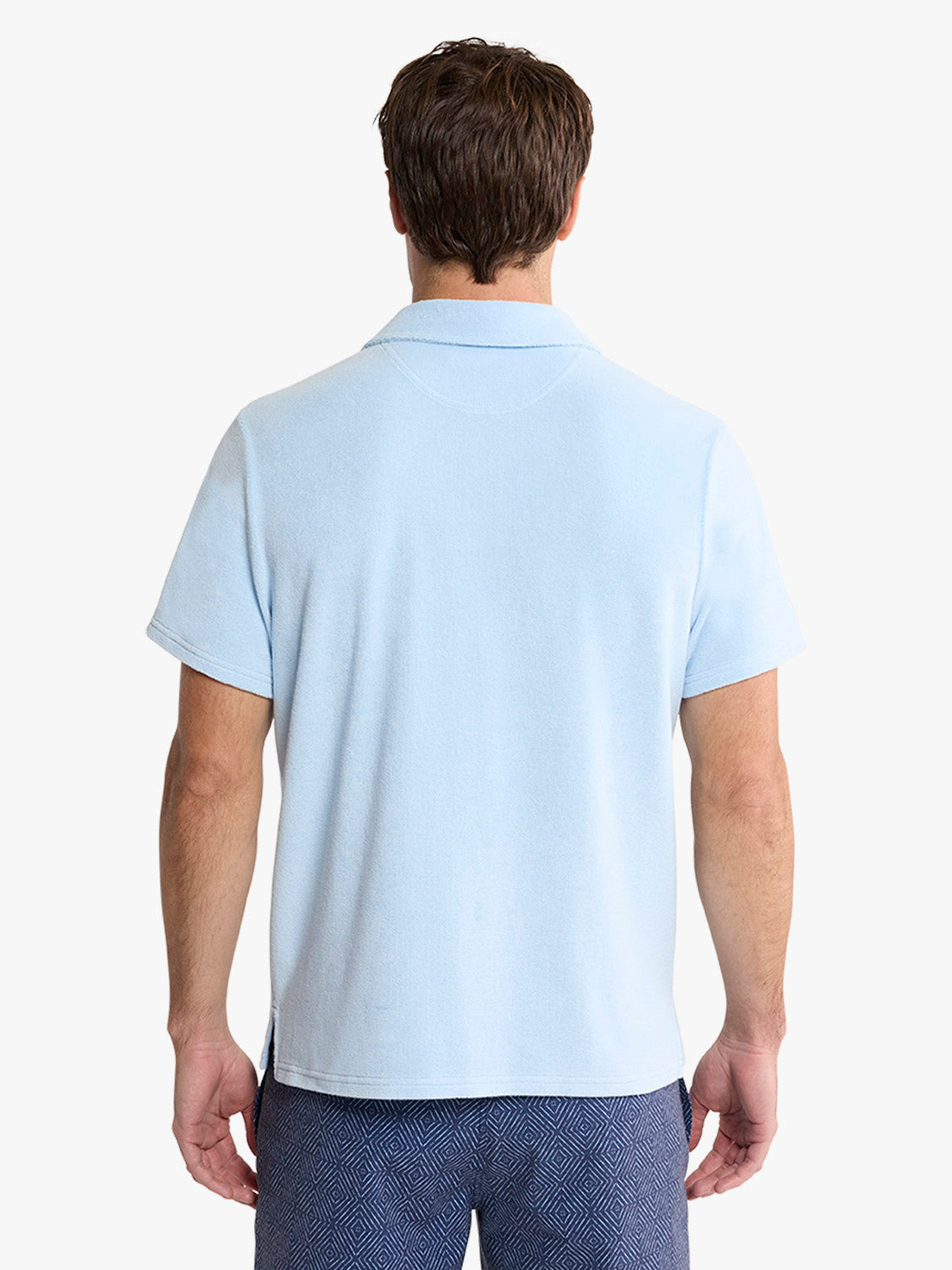 Man wearing a light blue short-sleeve polo shirt with a textured collar, shown from the back.