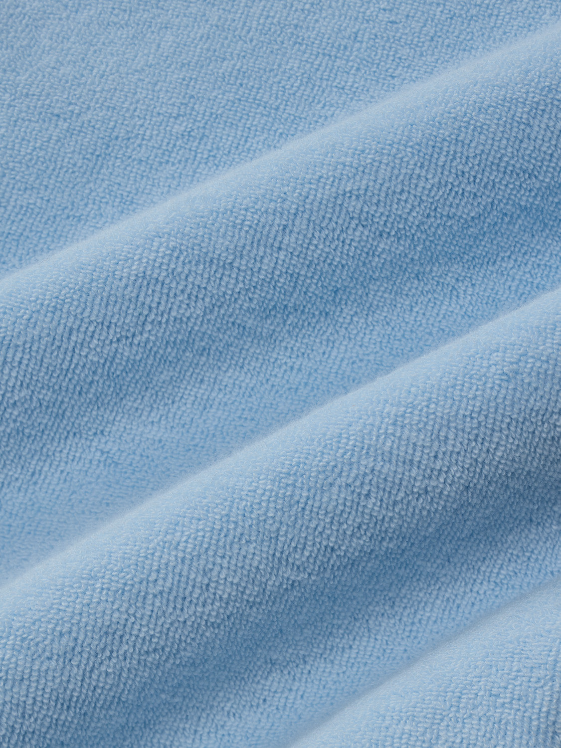 Light blue terry fabric with a textured, ribbed surface showing diagonal folds and draping details.