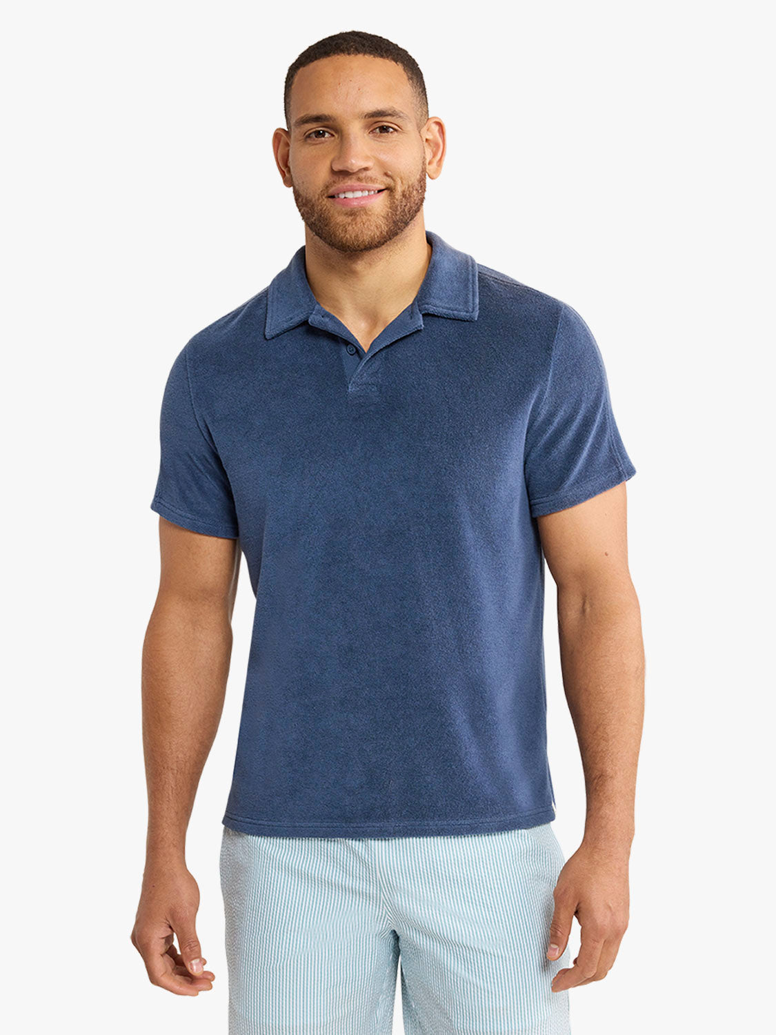 Man wearing a navy terry polo shirt with a collared neckline and short sleeves.
