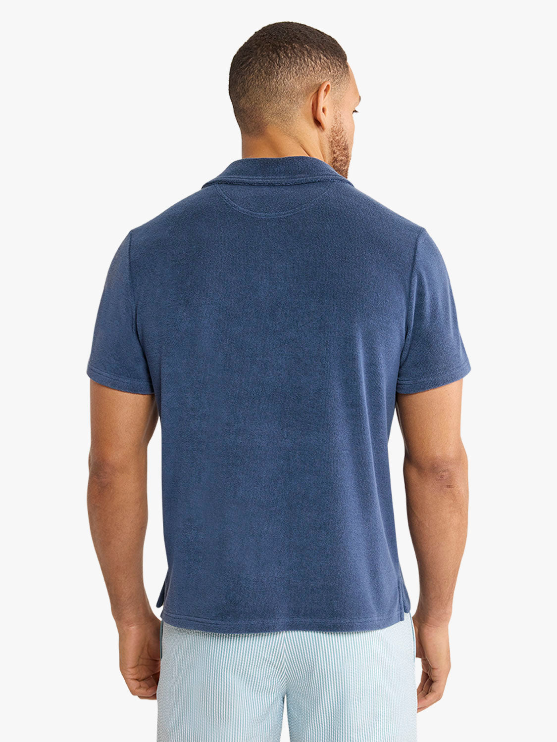 Man wearing a navy terry cloth short-sleeve polo shirt shown from the back view.