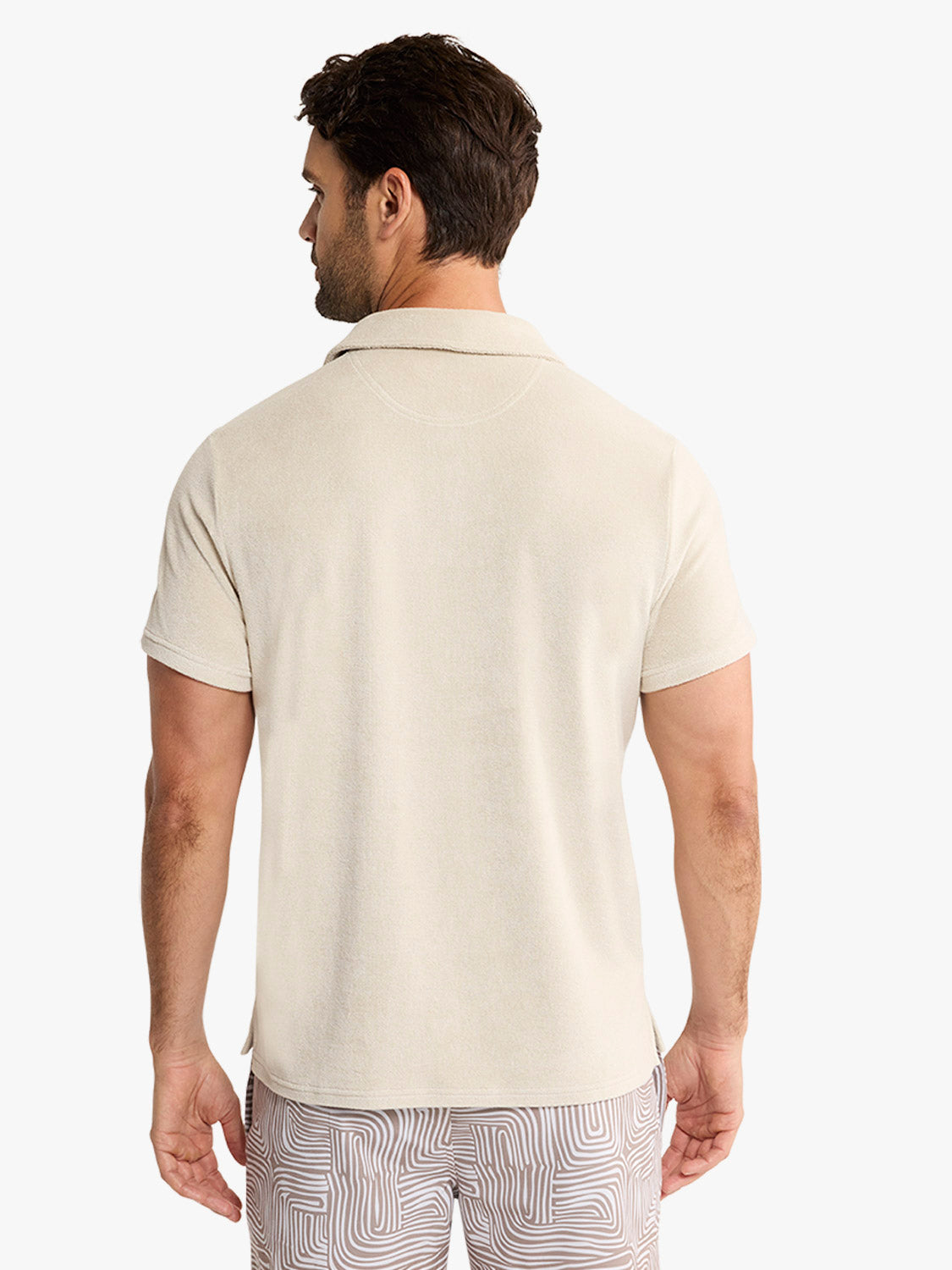 Man wearing a sand-colored short-sleeve terry polo shirt shown from the back.