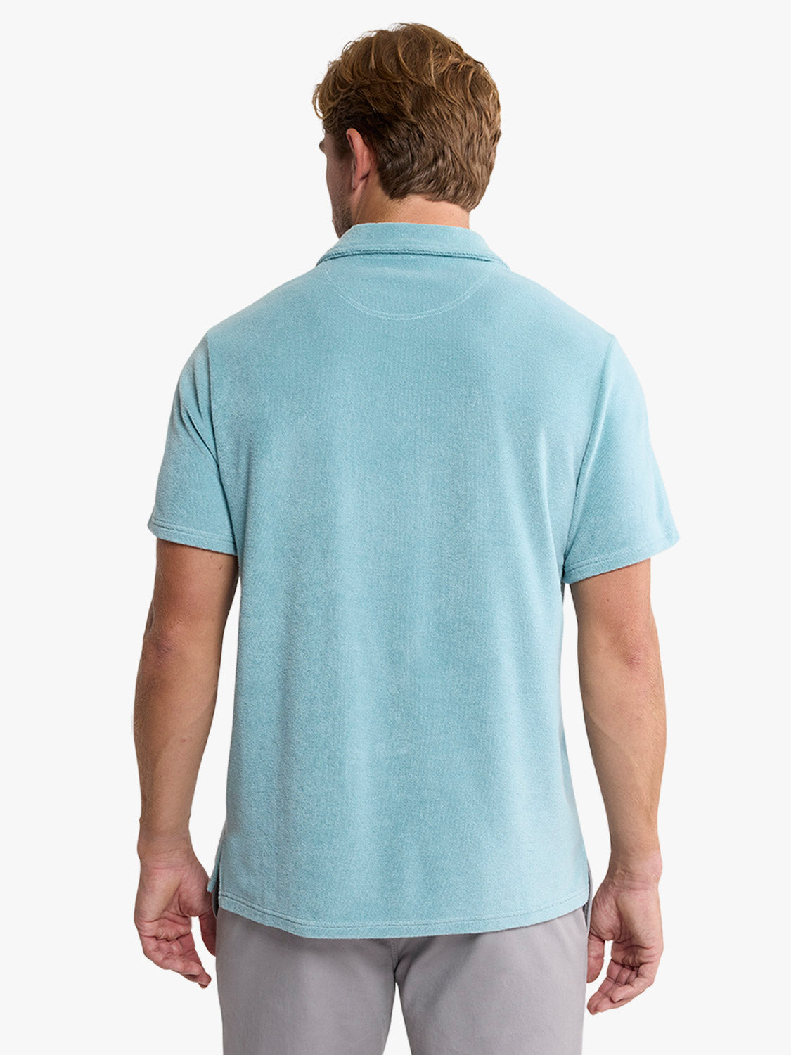Man wearing a light blue terry polo shirt with short sleeves and a collared neckline, shown from behind.