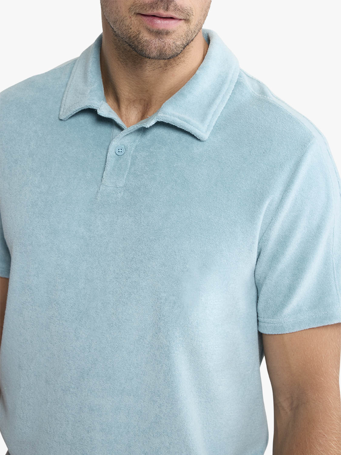 Man wearing a light blue terry polo shirt with short sleeves and button placket.