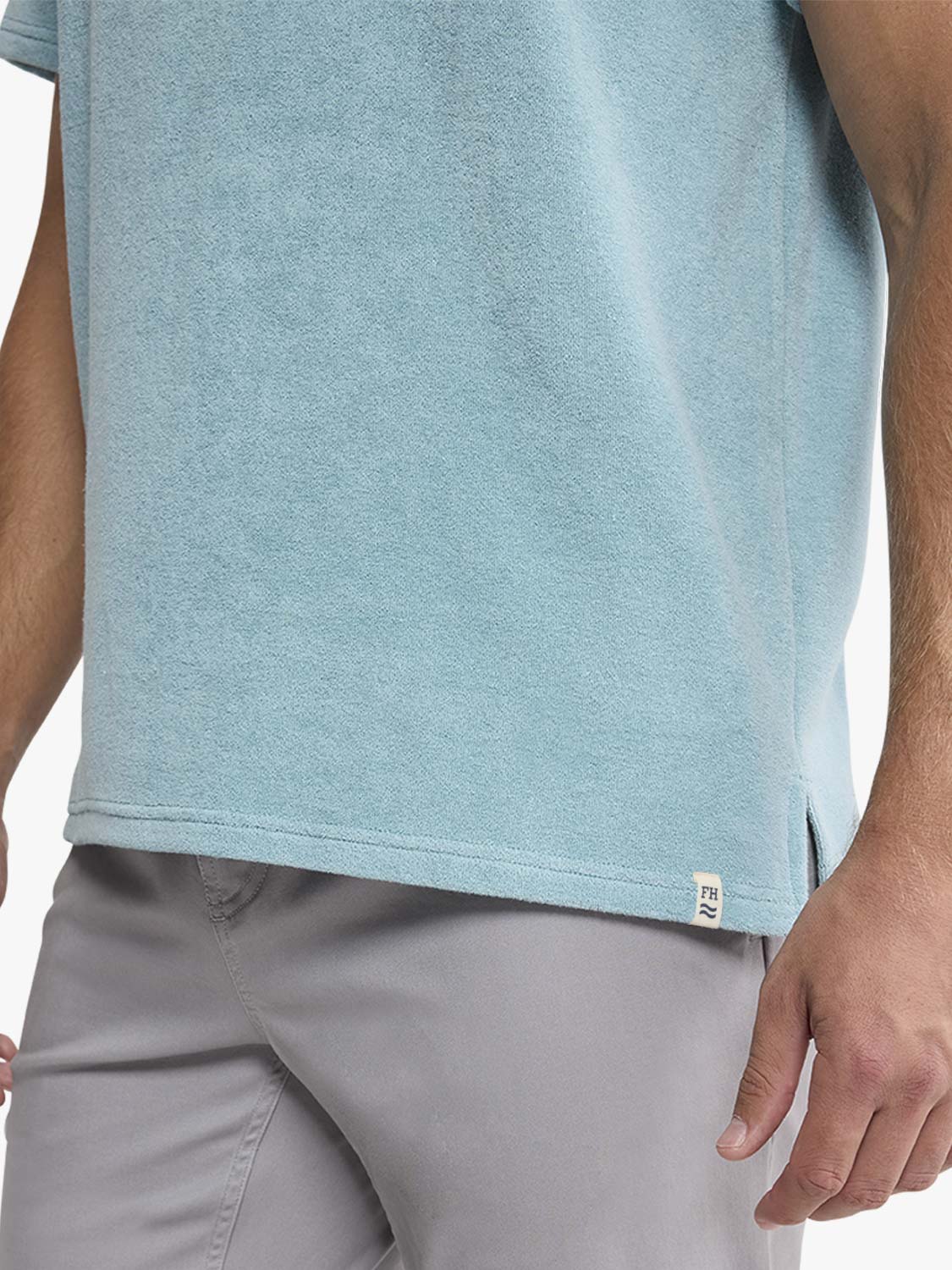 Man wearing a bay blue textured terry polo shirt with short sleeves and gray shorts.