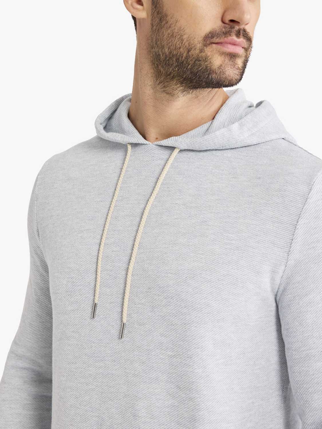 Man wearing a heather grey hoodie with drawstring and ribbed texture detail visible.
