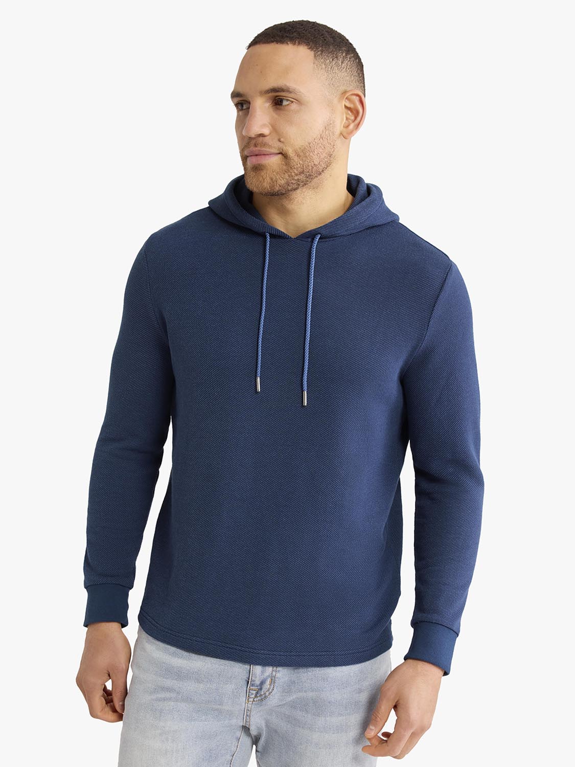 Man wearing a navy blue hoodie with drawstring and ribbed cuffs over light jeans.
