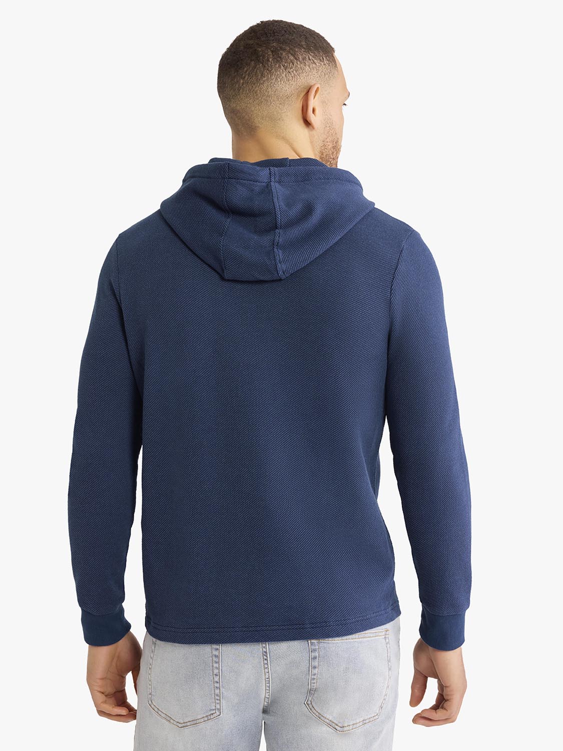 Man wearing a navy blue hoodie with a kangaroo pocket, shown from the back view.