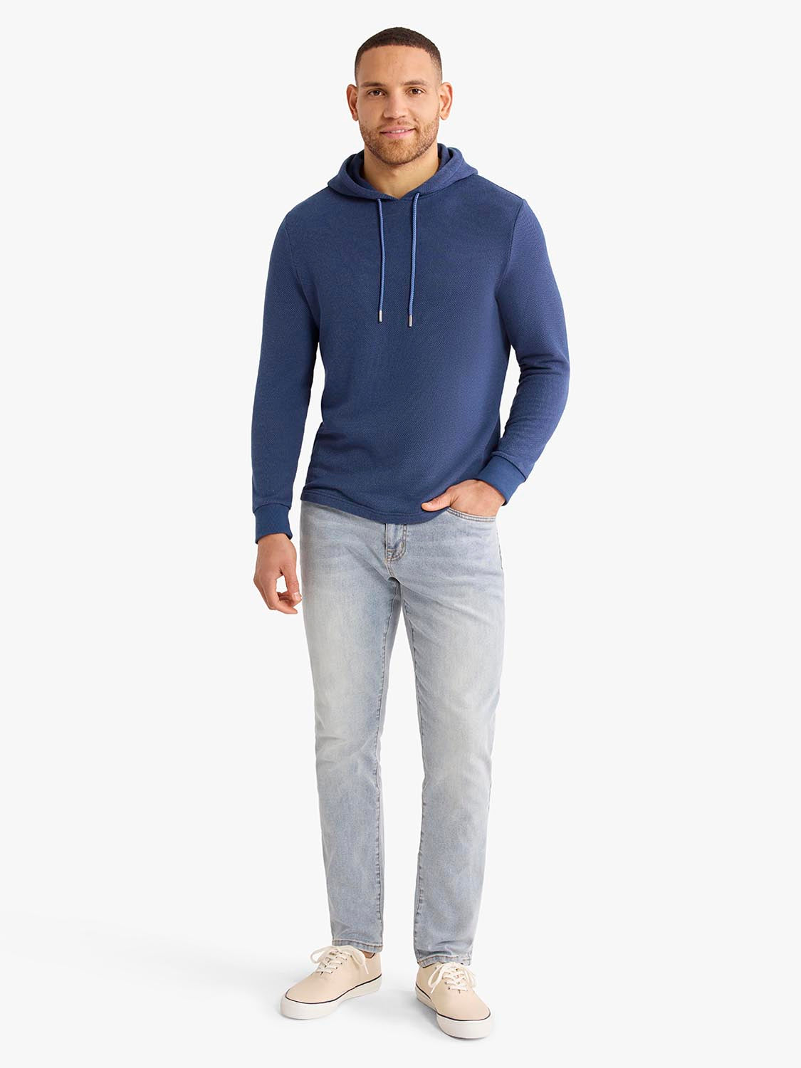 Man wearing a navy blue hoodie with drawstrings and light gray jeans.