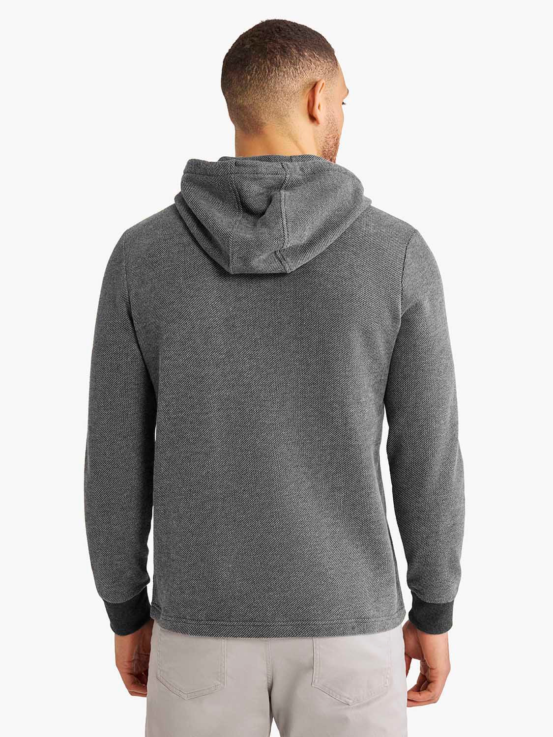 Man wearing a charcoal gray hoodie with drawstring hood and black ribbed cuffs, shown from behind.