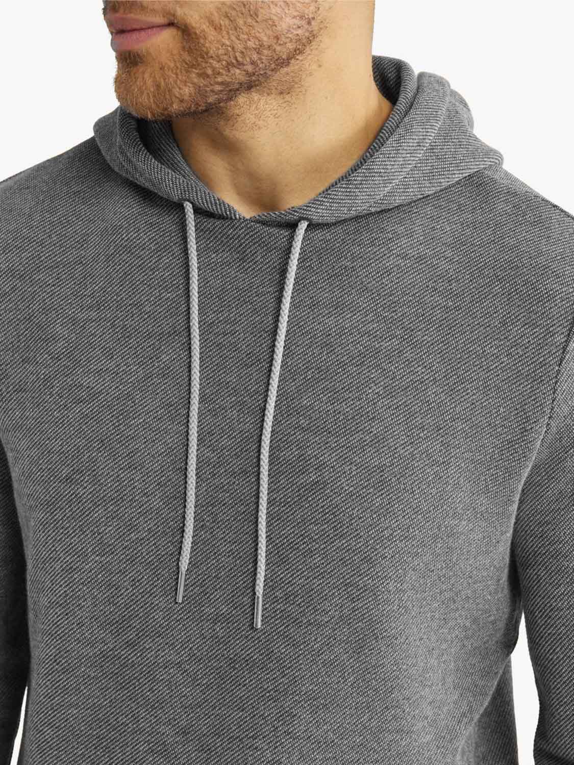 Man wearing a charcoal gray hoodie with gray drawstrings and textured fabric detail.