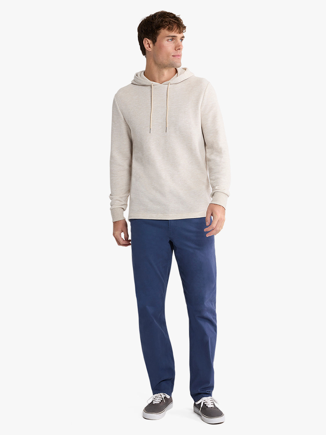 Man wearing a natural beige hoodie with drawstrings and navy blue pants.