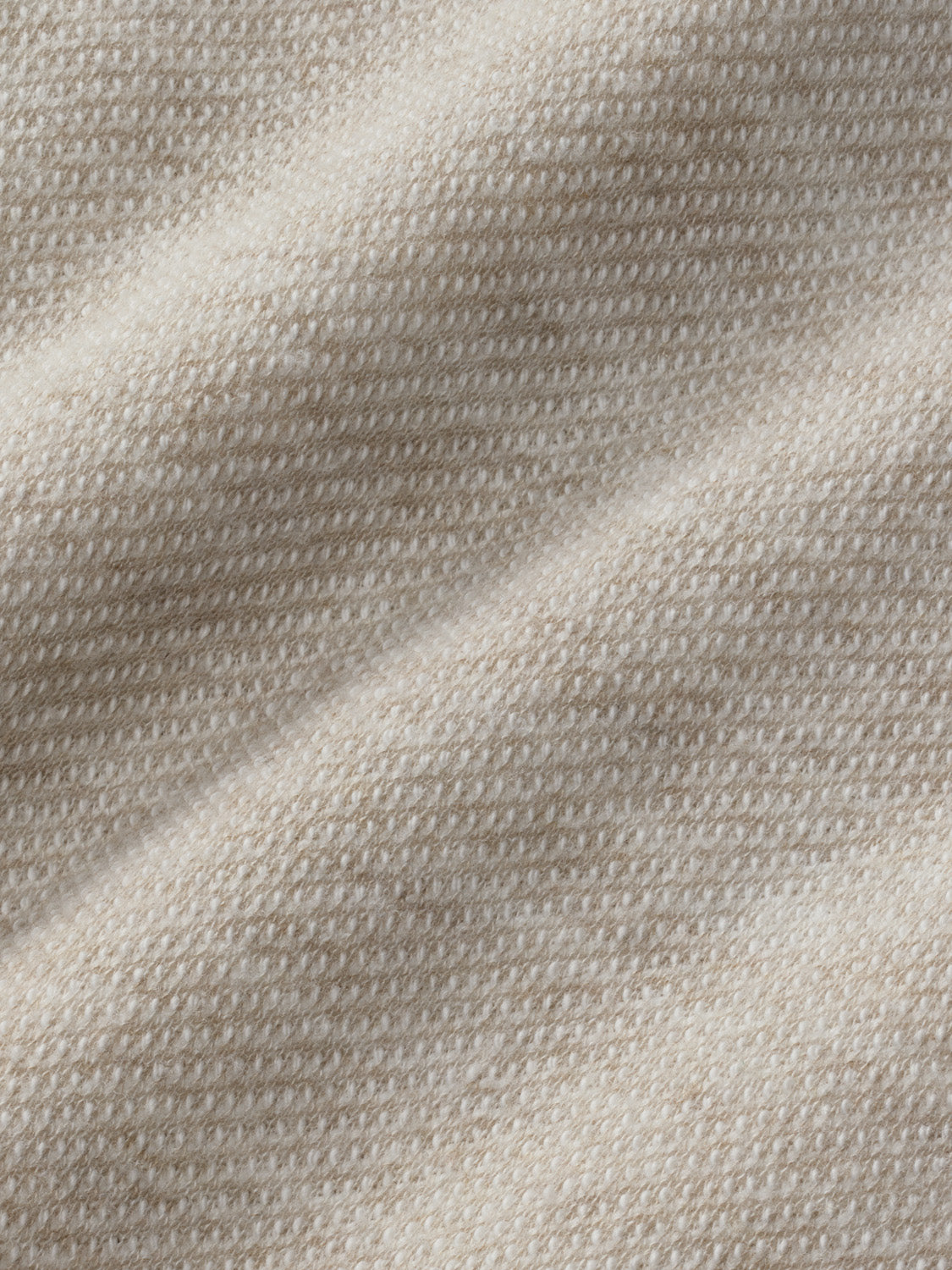 Beige textured fabric with a woven pattern and subtle folds throughout the garment.