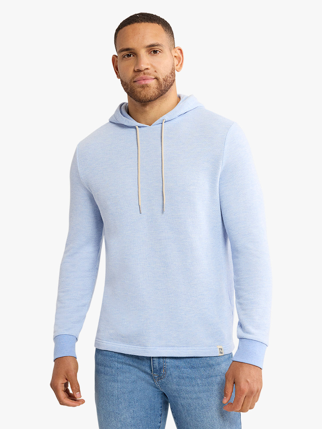 Man wearing a light blue hoodie with drawstrings and ribbed cuffs over blue jeans.