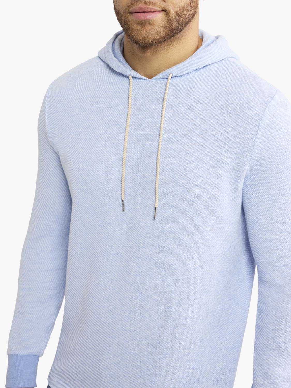 Man wearing a light blue hoodie with a drawstring hood and textured fabric.