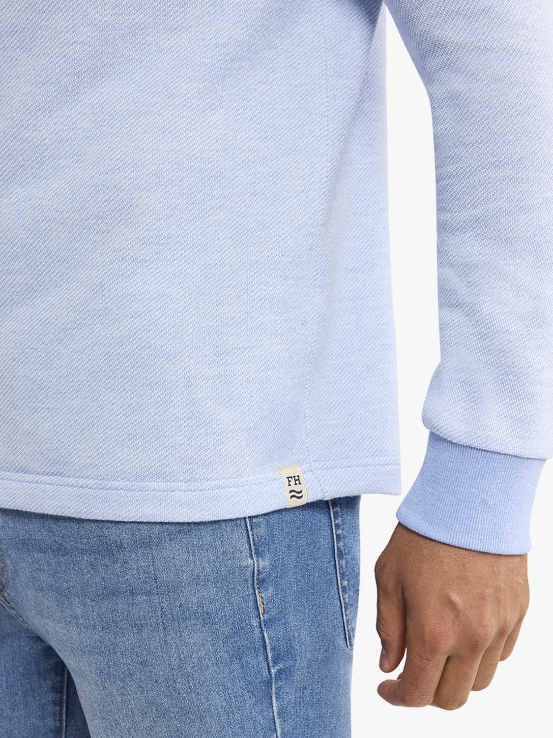 Light blue hoodie with ribbed cuffs worn over blue jeans, showing close-up detail of fabric and fit.
