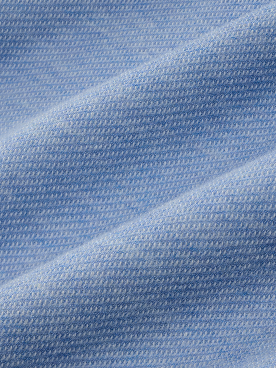 Light blue textured fabric with a knit pattern showing woven surface detail and folds.