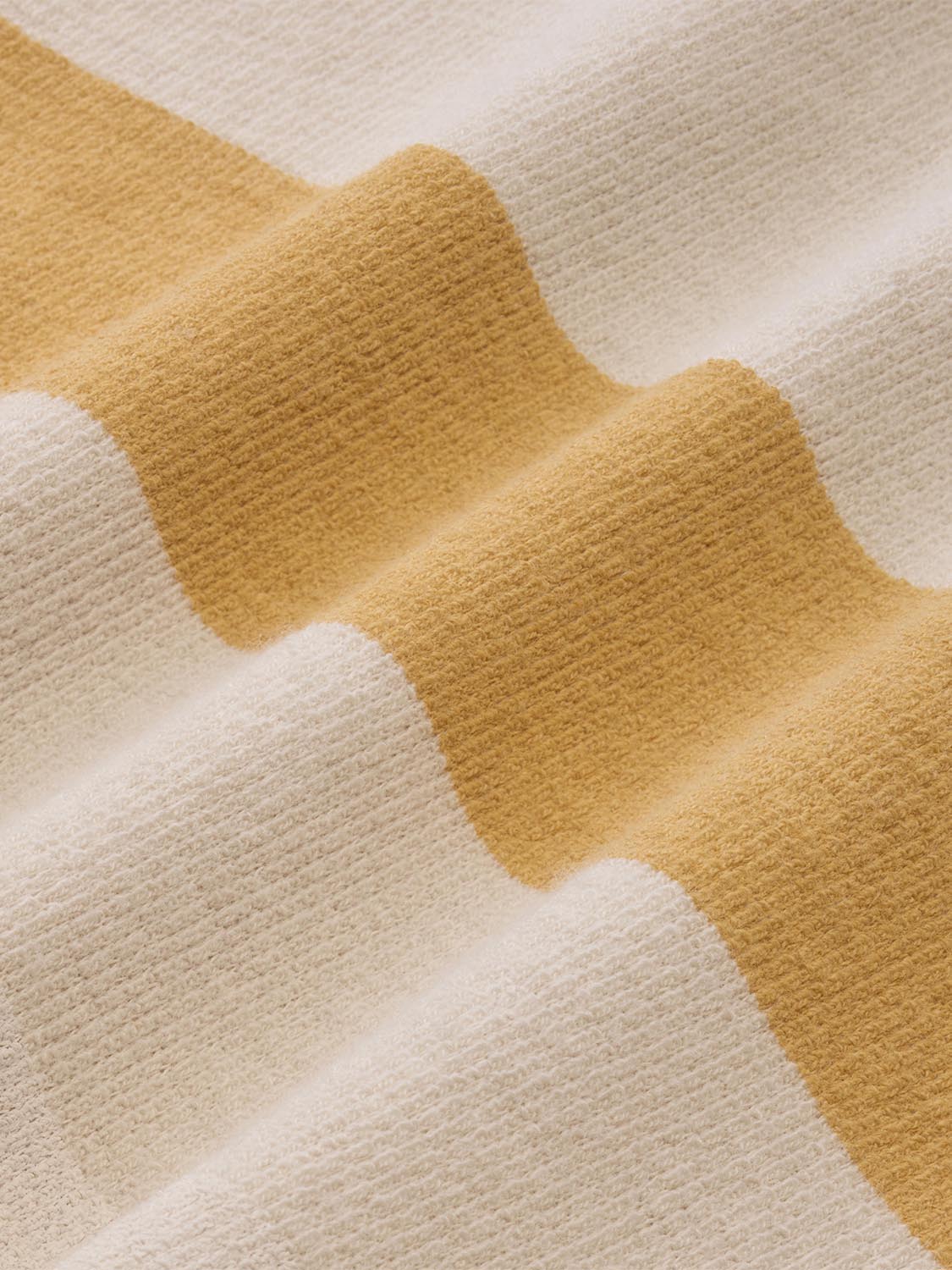 Textured terry fabric with alternating golden yellow and cream striped pattern in wavy bands.