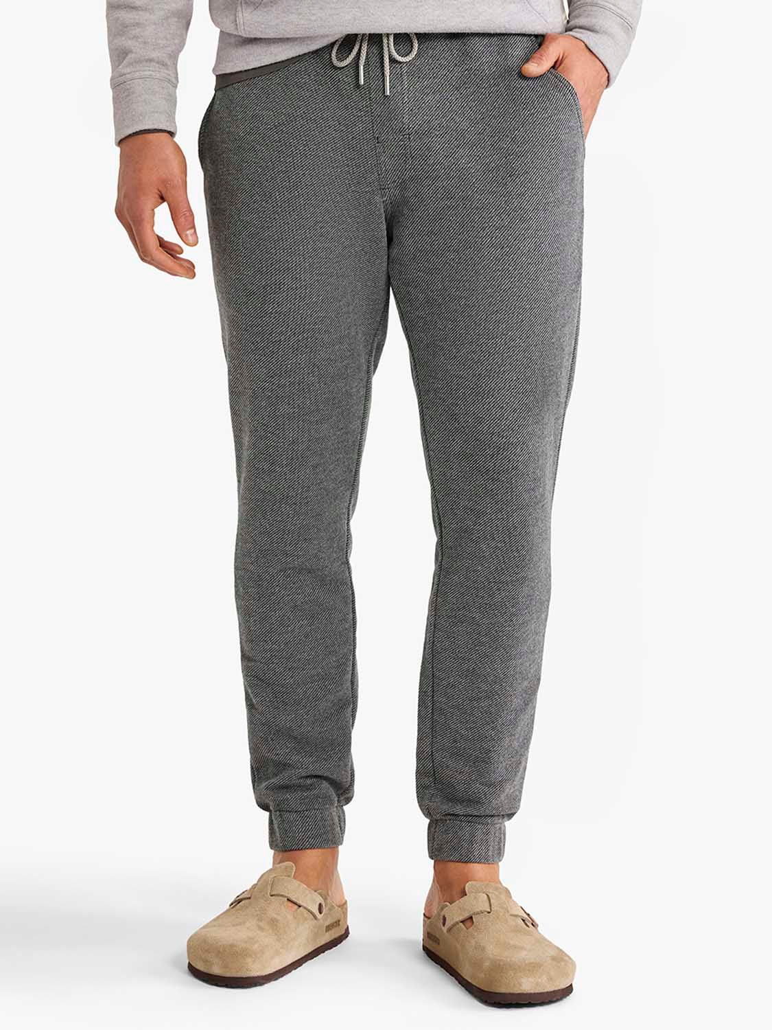 Charcoal sweatpants with drawstring waist and ribbed cuffs worn with a gray sweatshirt.