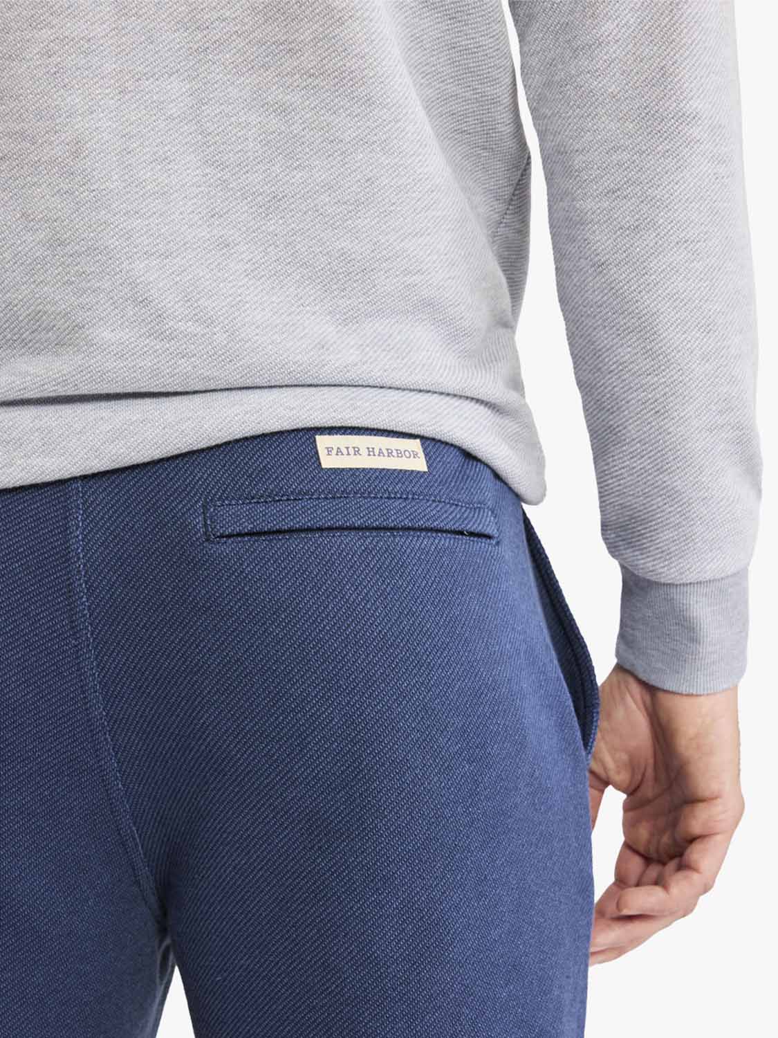 Navy sweatpant with flat front waistband and ribbed knit cuffs, worn with gray long-sleeve shirt.