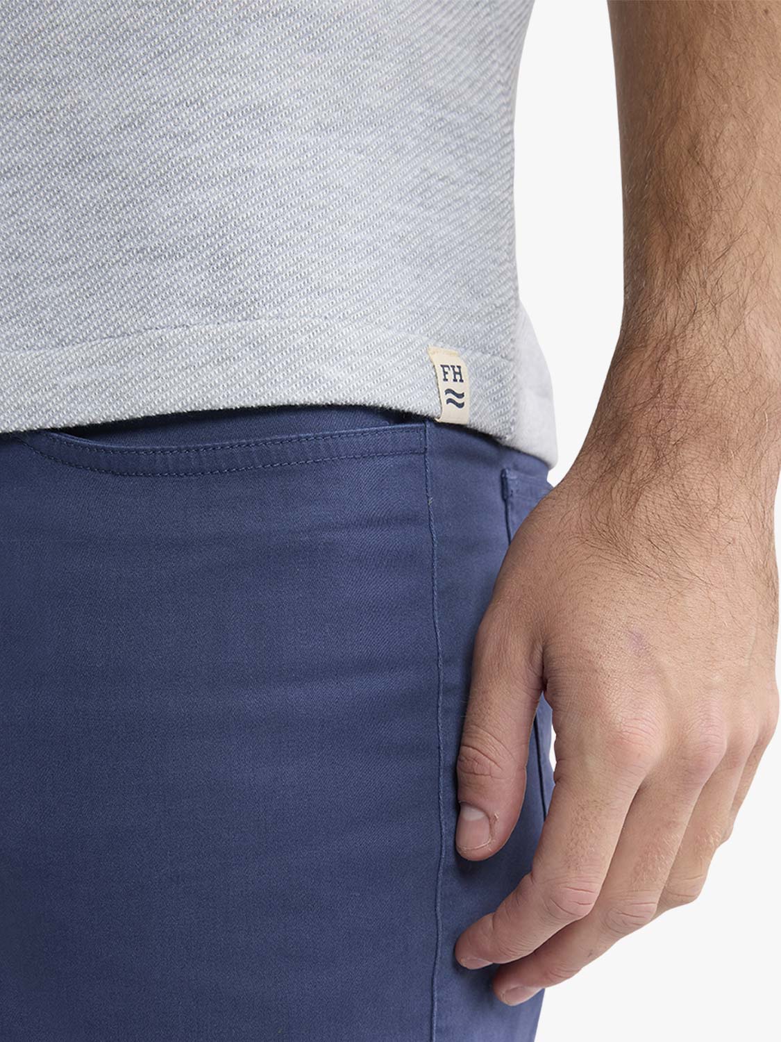 Man wearing heather grey polo shirt with navy shorts, showing textured fabric detail and brand label.