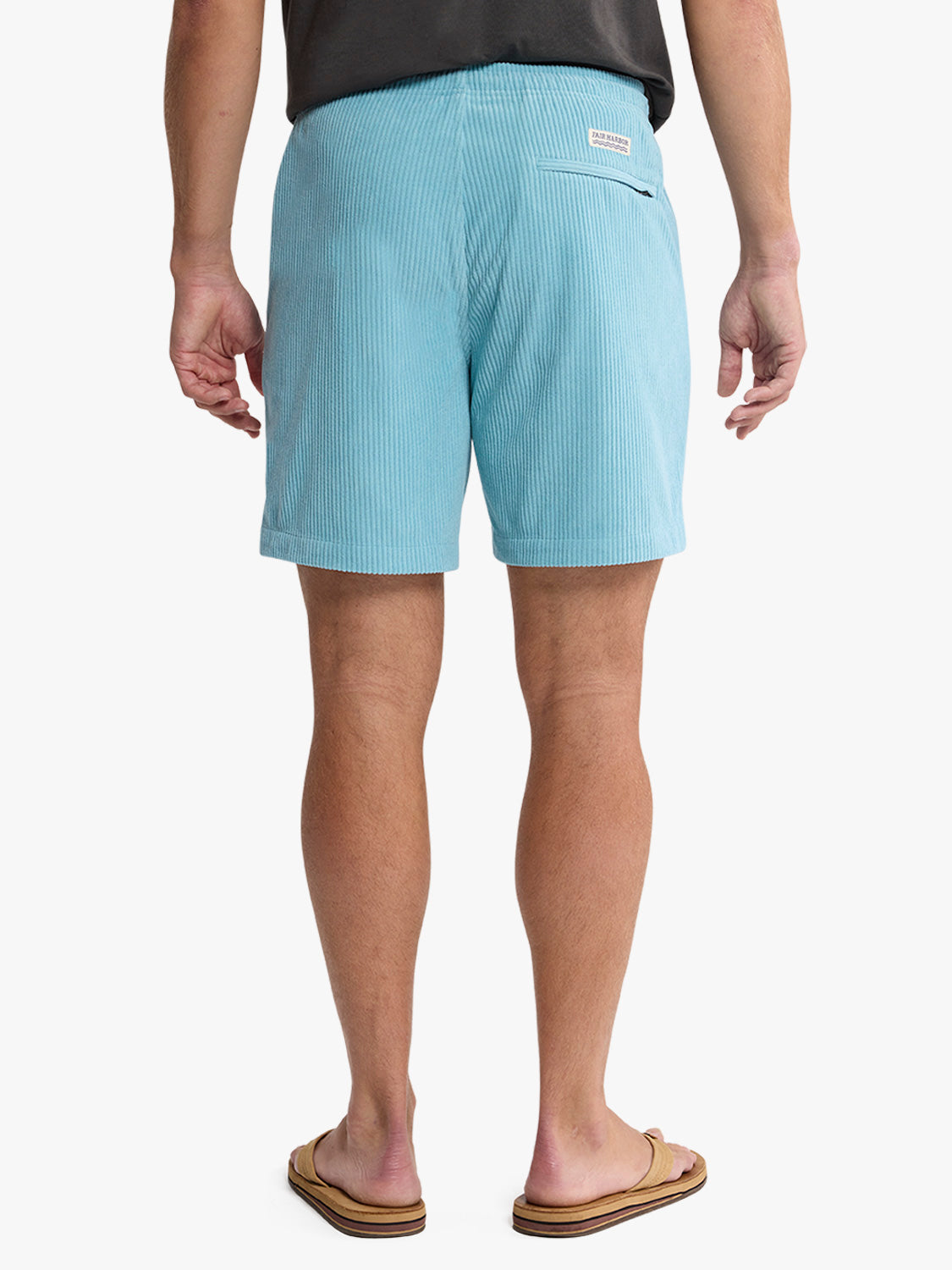 Man wearing light blue corduroy shorts with a back pocket, viewed from behind.