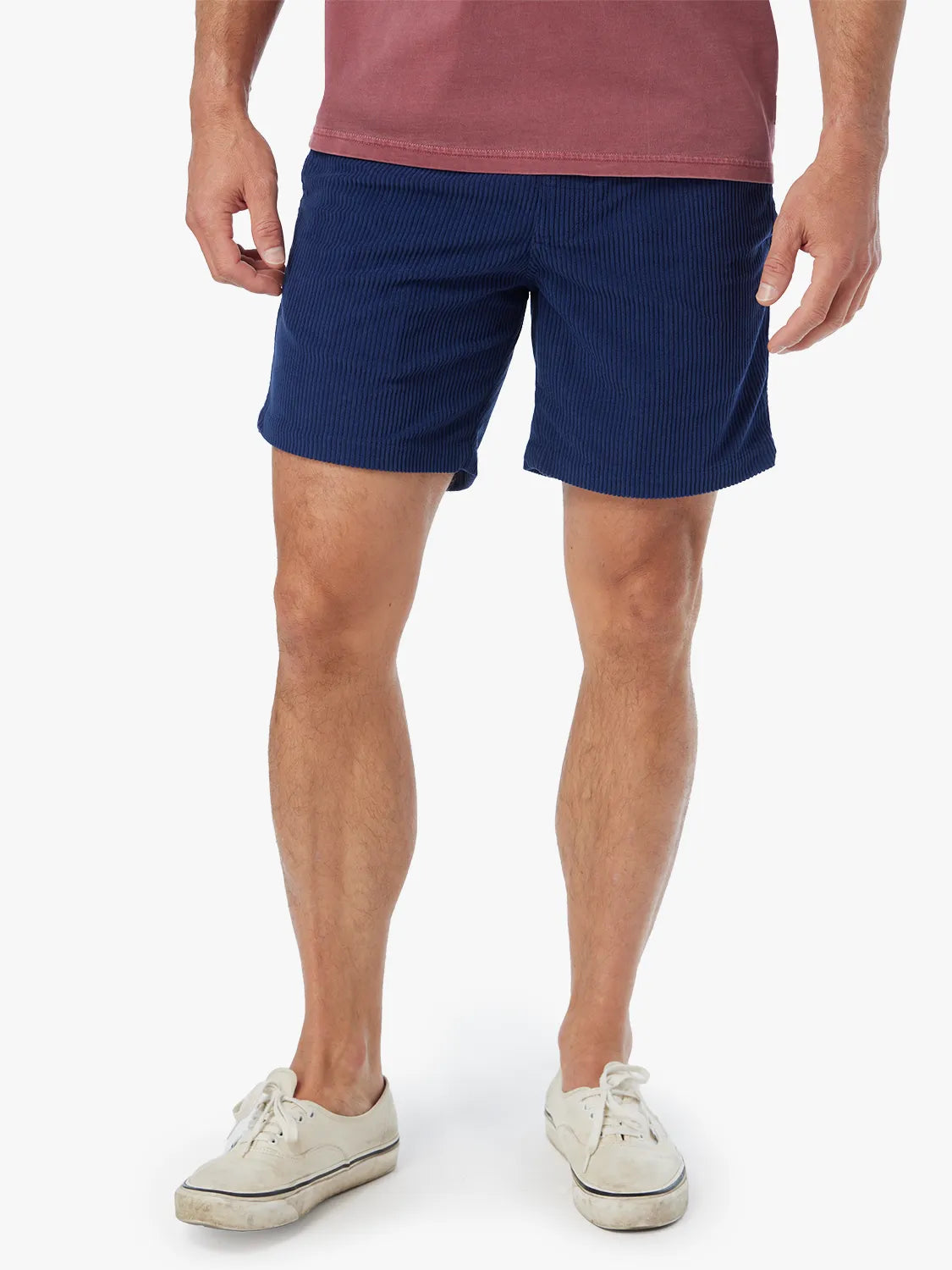 Man wearing navy corduroy shorts with vertical ribbed texture and white canvas sneakers.