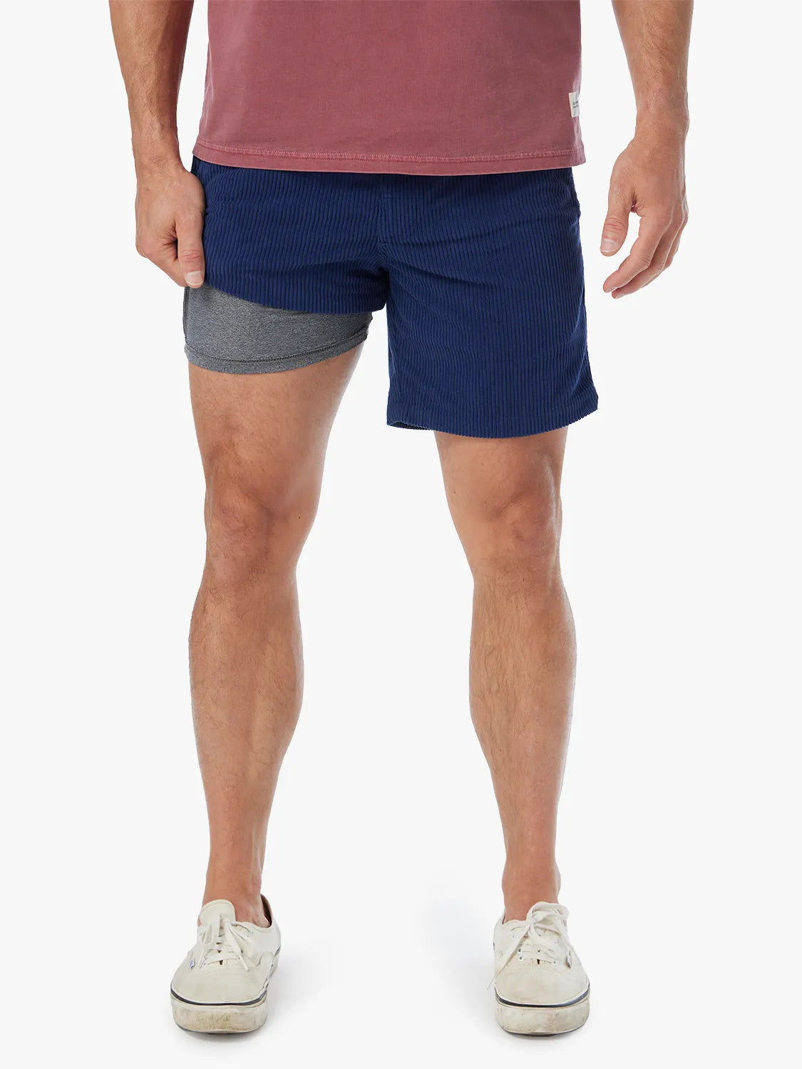 Man wearing navy corduroy shorts with gray waistband and white sneakers.