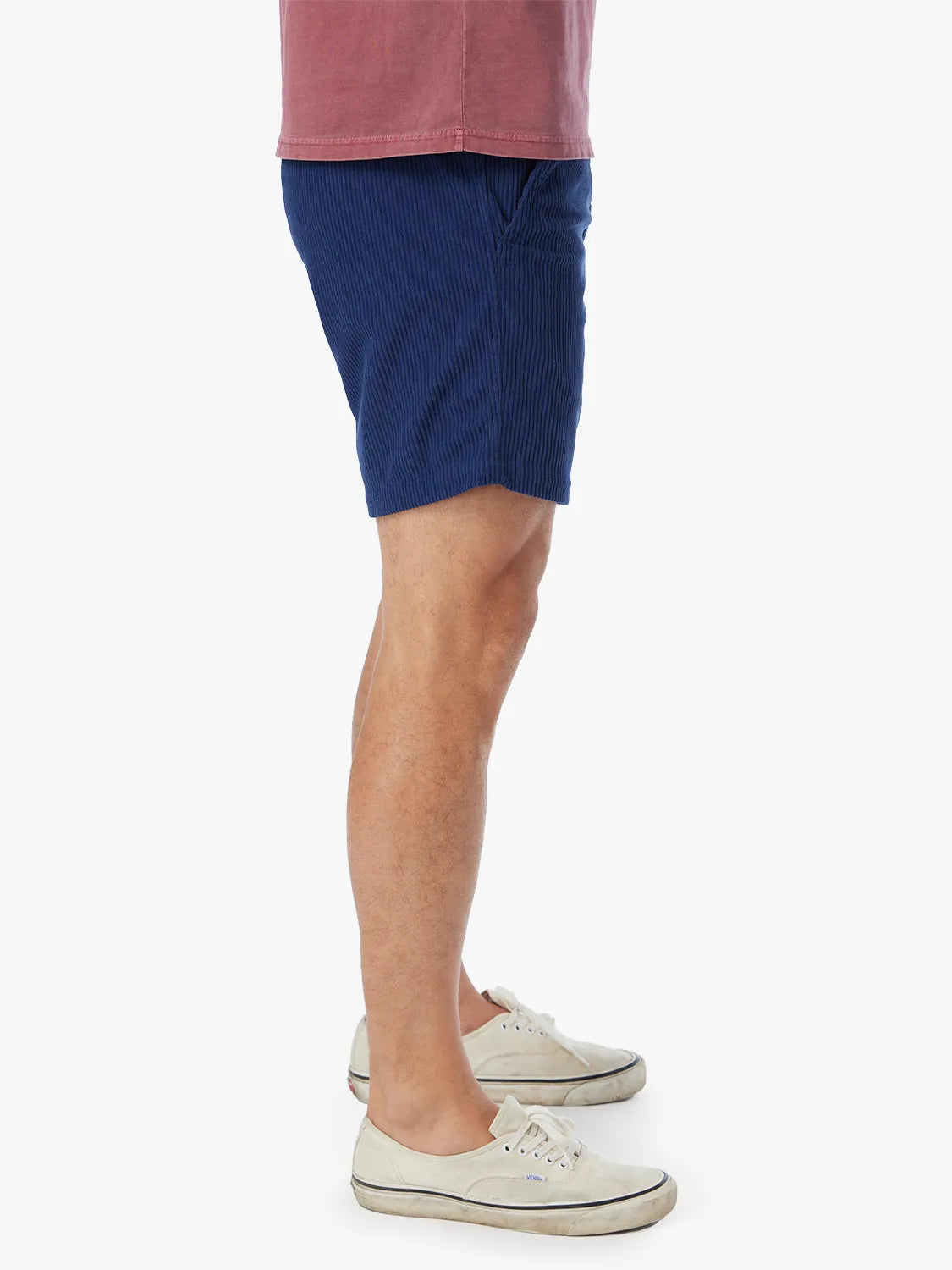 Navy corduroy shorts with vertical ribbed texture worn with cream canvas sneakers.
